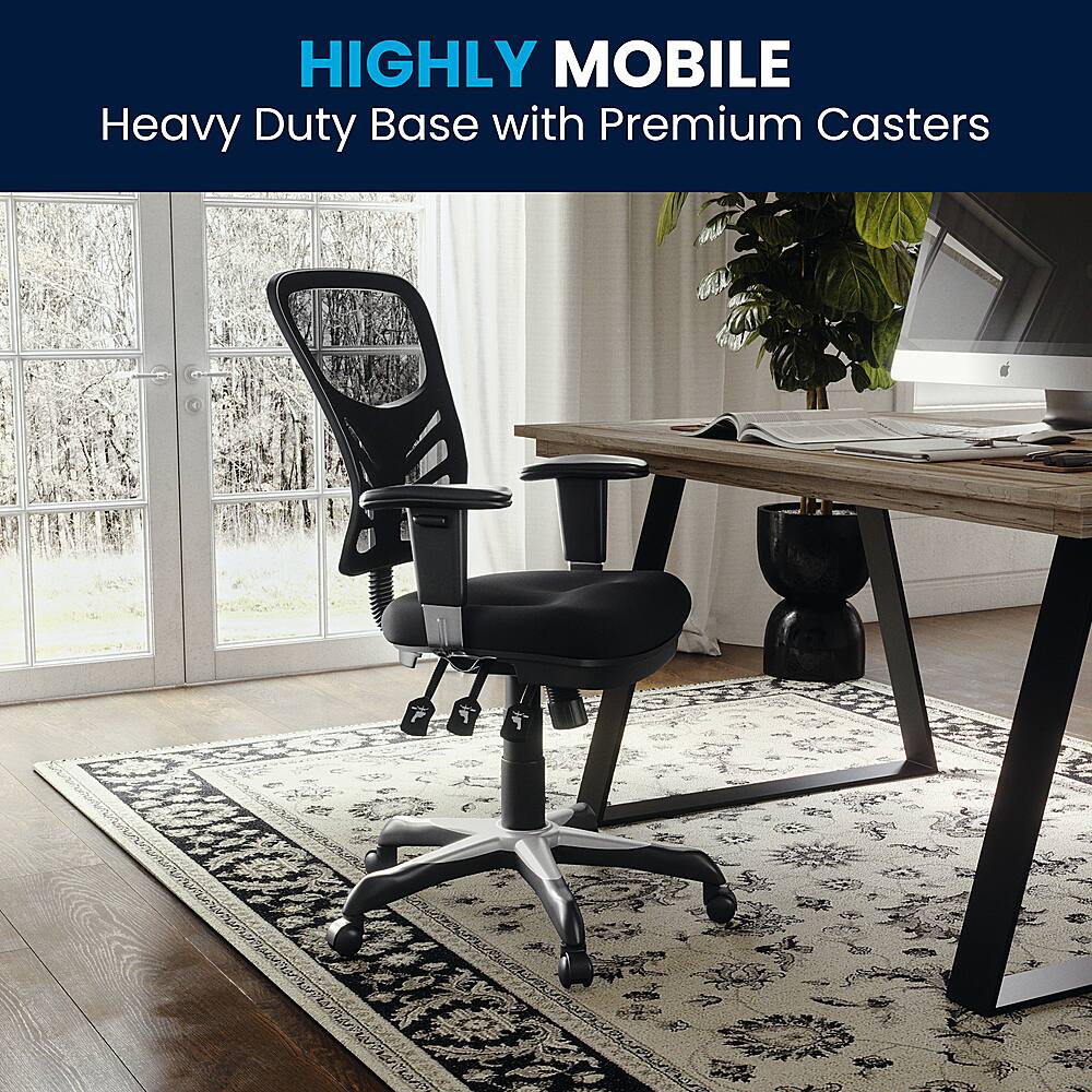 The image features a black office chair with a heavy duty base and premium casters. The chair is placed on a rug in front of a wooden desk, which has a laptop and a potted plant on it. The desk is situated near a window, providing a pleasant view for the person working at the desk. The combination of the comfortable chair, the well-organized desk, and the natural light from the window creates a pleasant and productive workspace.