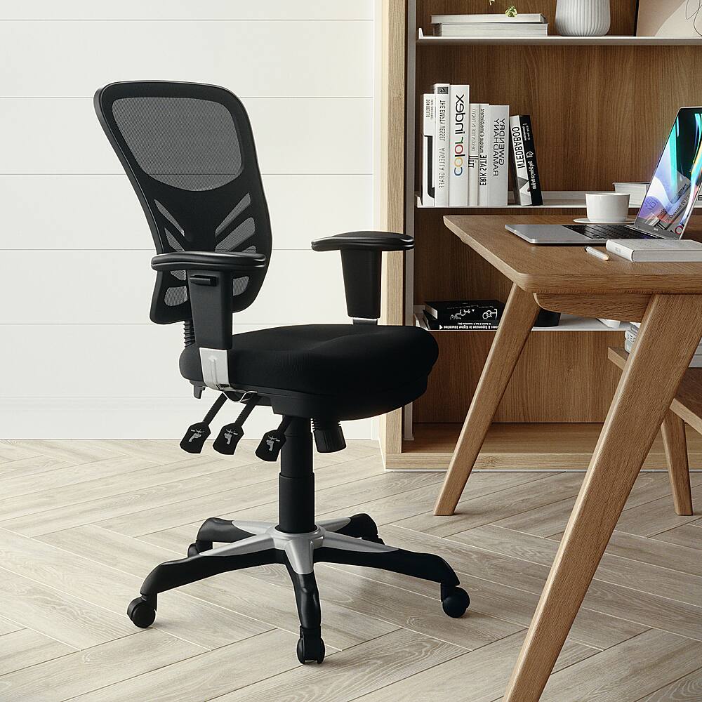 The image features a black office chair with wheels, positioned in front of a wooden desk. The desk has a laptop, a keyboard, and a mouse on it. There are also several books scattered around the desk, and a cup can be seen placed nearby. The overall scene suggests a workspace or home office setup.