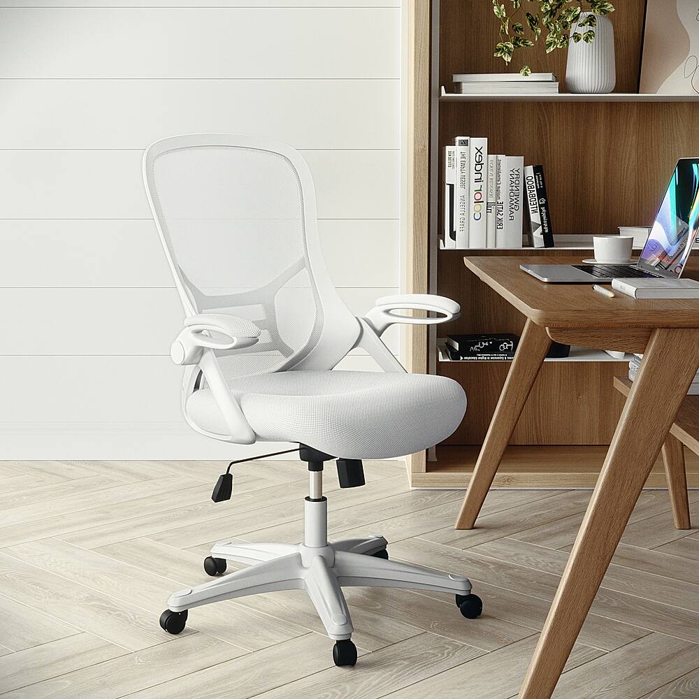 The image features a white office chair placed on a wooden floor next to a wooden desk. The desk is equipped with a laptop and a keyboard, and there are several books scattered around the area. Additionally, there is a potted plant and a vase on the desk, adding a touch of greenery and decoration to the workspace.