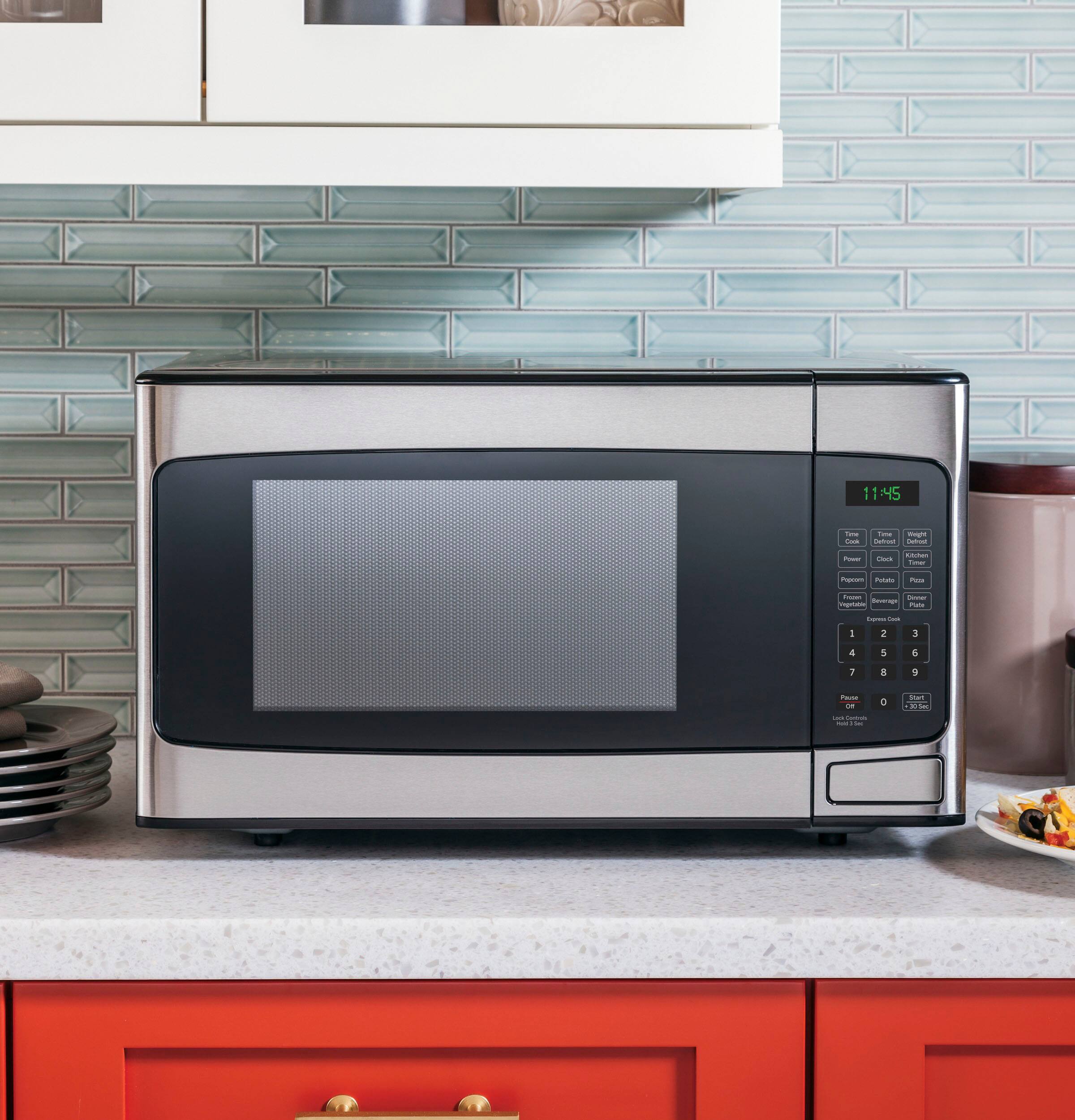 Left. GE - 1.1 Cu. Ft. Mid-Size Microwave with Included Pasta/Veggie Cooker - Stainless Steel.