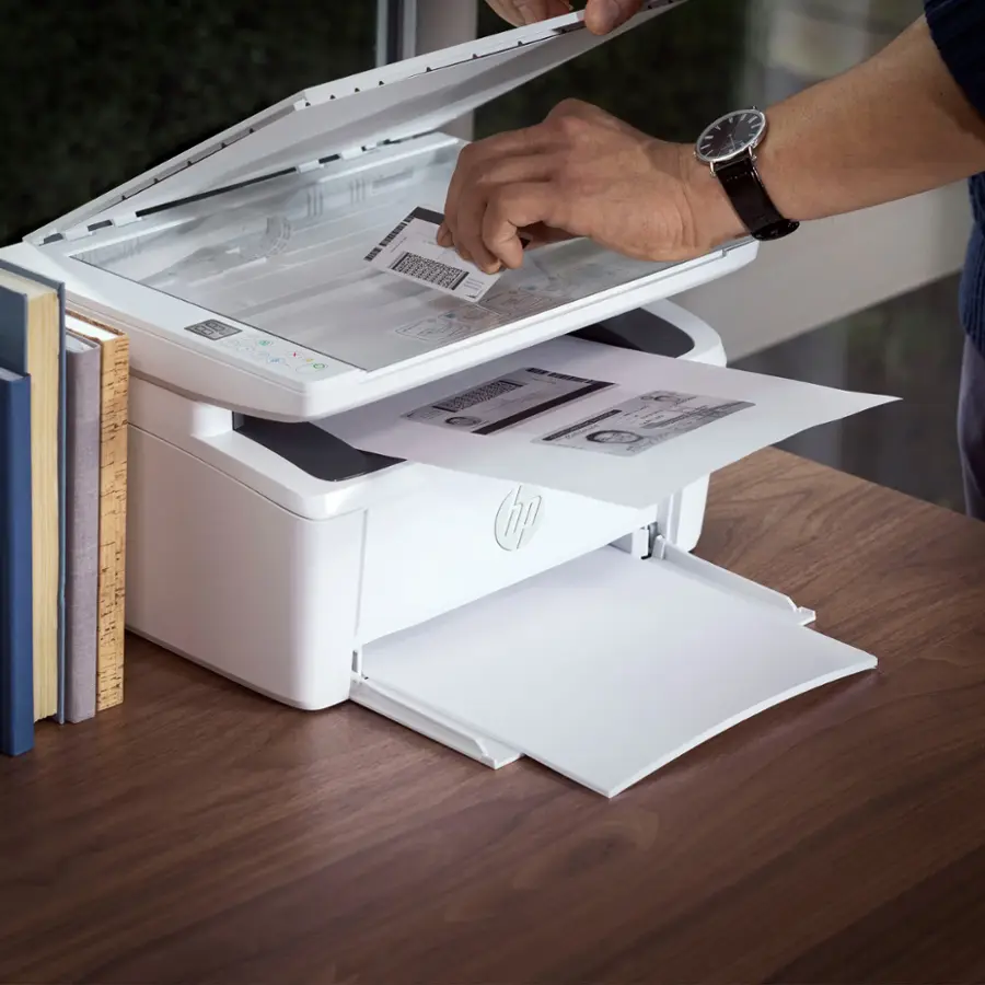 The image shows a person using a HP printer to copy both sides of an ID card onto one side of a piece of paper. The printer is placed on a desk, and the person is actively engaged in the process. The printer is designed to make it easy to copy both sides of ID cards onto a single sheet of paper, providing a convenient and efficient way to reproduce important documents.