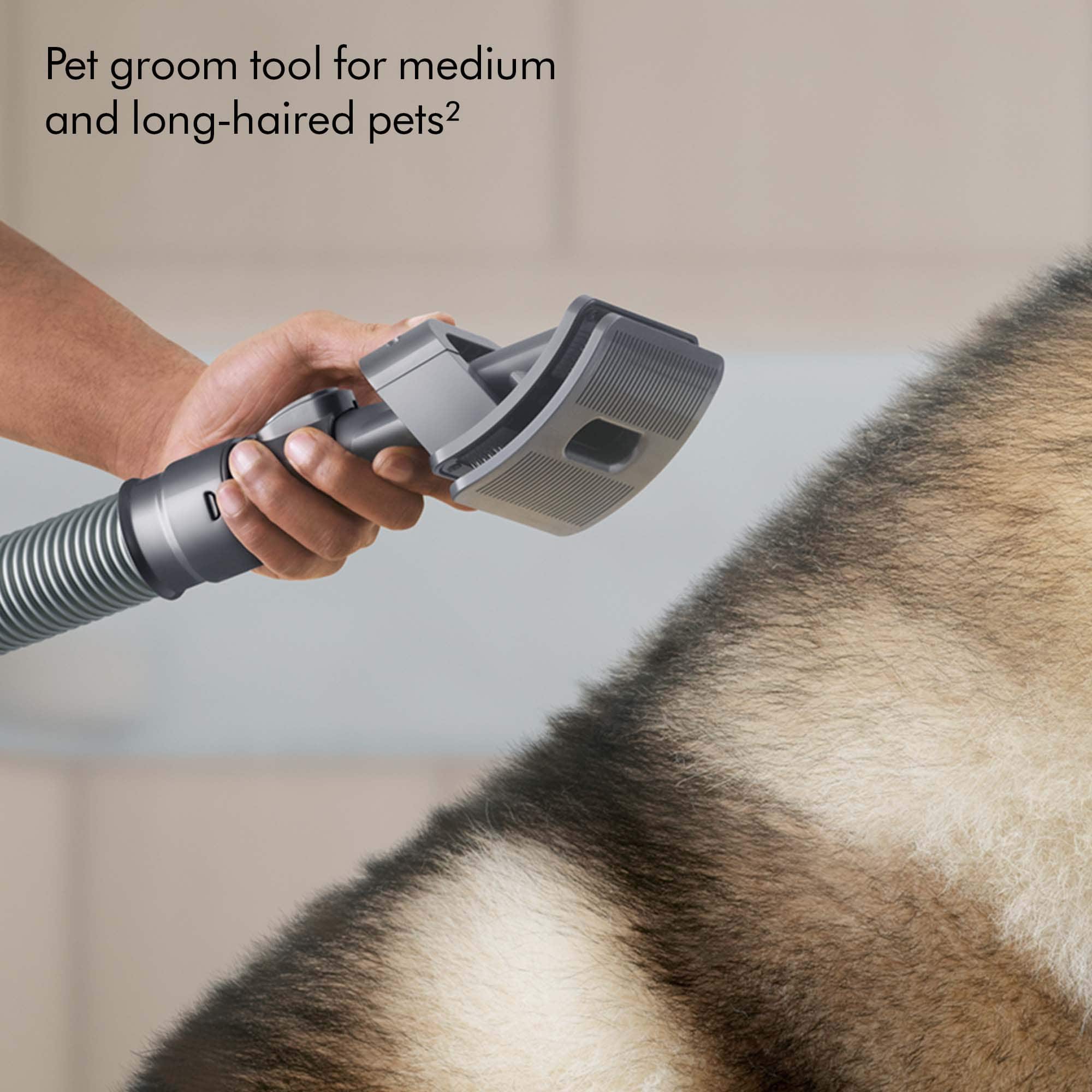 The image shows a person using a pet grooming tool on a dog. The tool is designed for medium and long-haired pets, making it suitable for grooming dogs with thick or long fur. The person is holding the tool close to the dog's fur, likely to clean or style it. The scene suggests that the person is taking care of the dog's grooming needs, ensuring its fur remains clean and well-maintained.