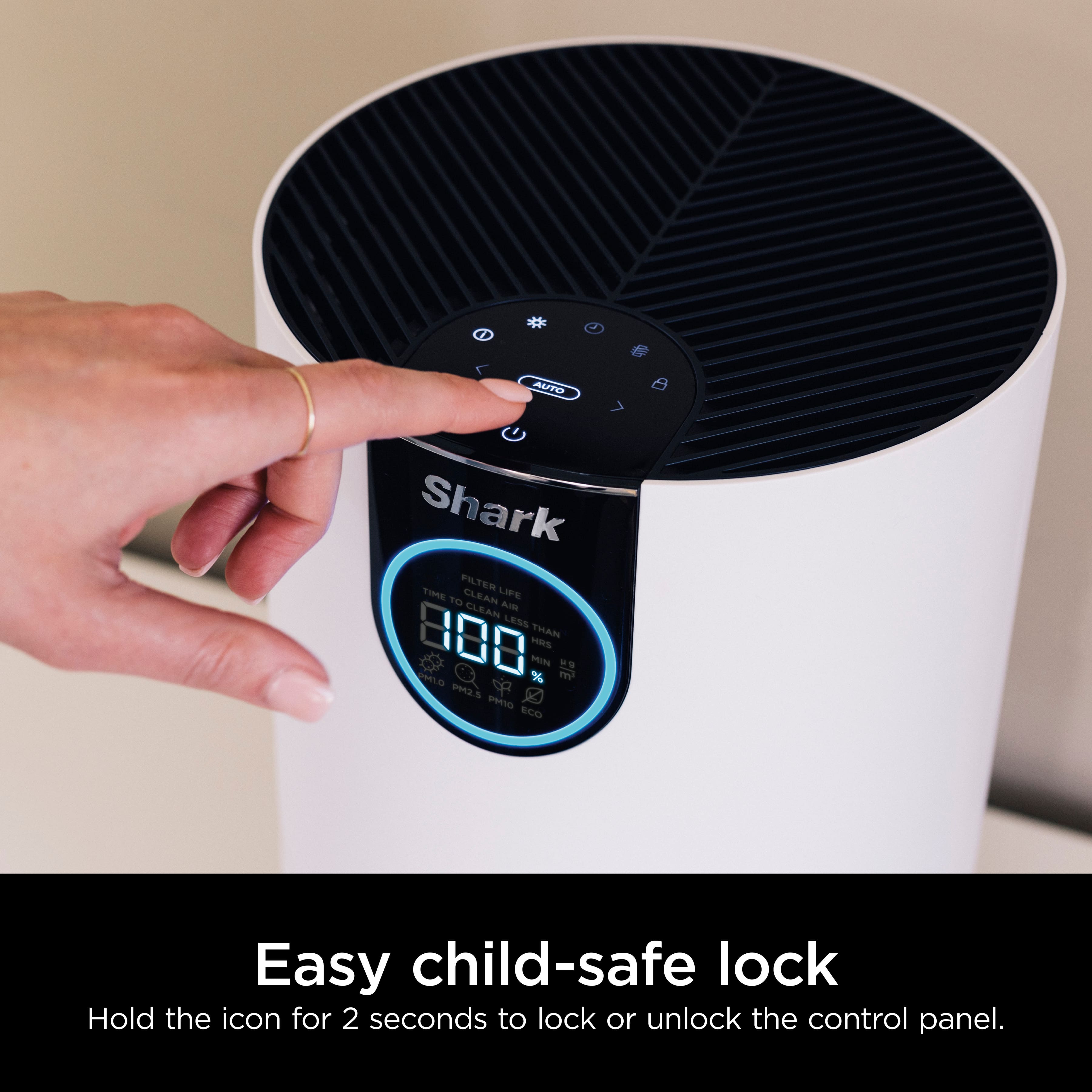The image shows a person's hand pressing a button on a white appliance, which is a Shark vacuum cleaner. The appliance has a child-safe lock feature that allows the user to lock or unlock the control panel by holding the icon for 2 seconds. This feature ensures that children cannot accidentally turn on the vacuum cleaner or change settings, making it a safer and more convenient option for households with young children.