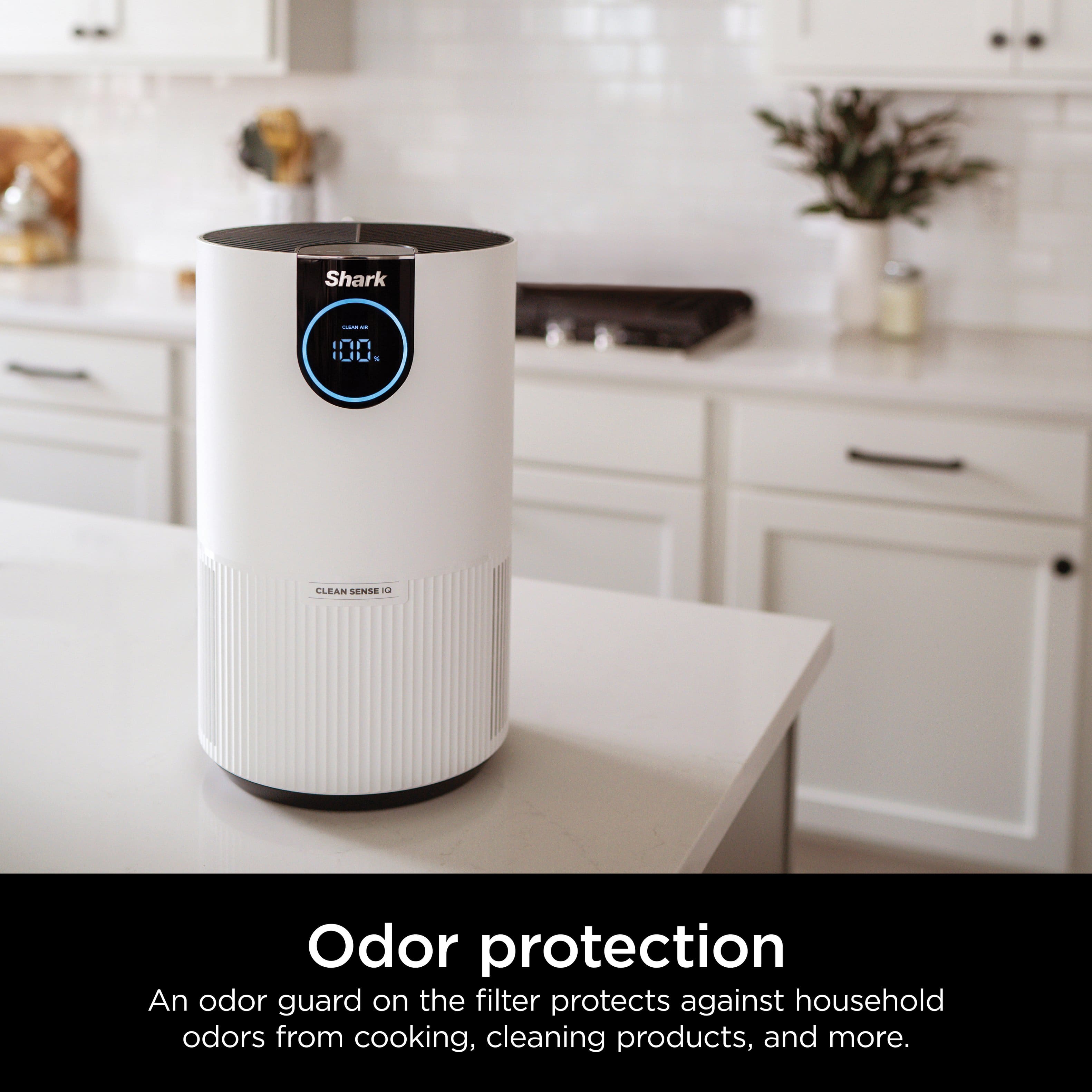 The image features a white Shark air purifier sitting on a countertop in a kitchen. The air purifier is designed to protect against household odors from cooking, cleaning products, and more. It is an effective solution for maintaining a fresh and clean environment in the home.