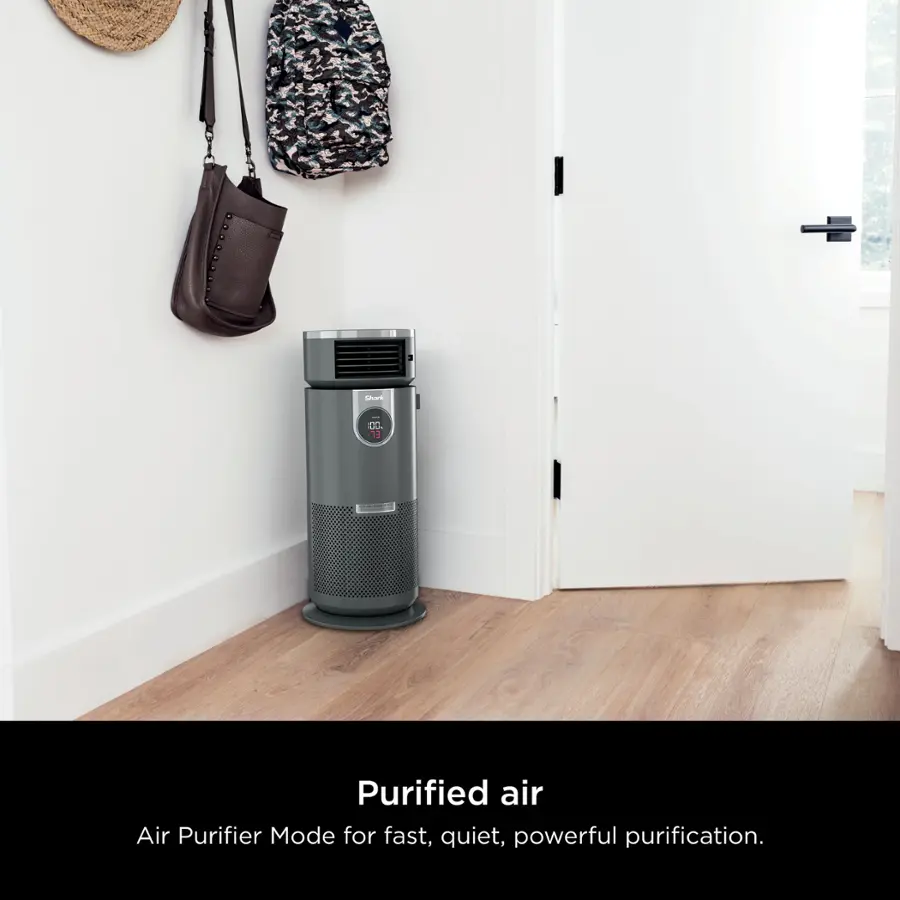 The image features a purified air air purifier placed in a room. The air purifier is positioned next to a door, and there is a handbag hanging on the wall above it. The room appears to be clean and well-organized, with a focus on the air purifier as the main subject.