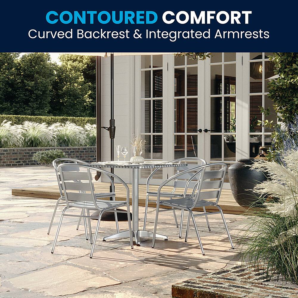 The image features a patio setting with a dining table and chairs. The table is accompanied by chairs with curved backrests and integrated armrests, providing a comfortable and relaxing seating experience. The table is also adorned with wine glasses, adding to the ambiance of the outdoor dining experience.