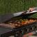 The image features a Blackstone grill with a person opening it up to reveal a variety of food being cooked. The grill is filled with different types of food, including meat and vegetables. The person is actively engaged in the process of opening the grill, likely preparing to serve the delicious meal.
