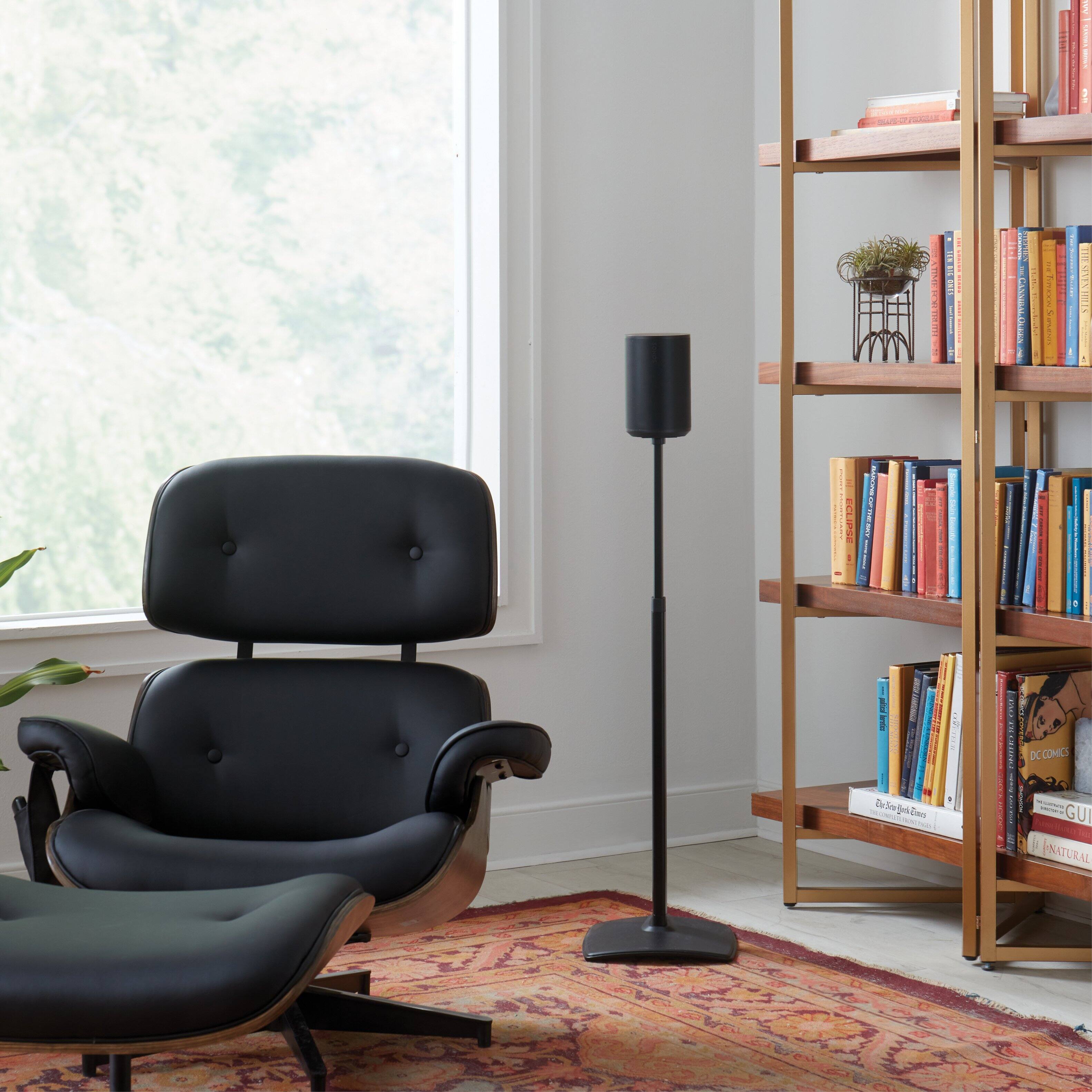 The living room features a black chair, a lamp, and a bookshelf filled with books. The bookshelf is made of wood and has a variety of books on it, including some red books. The chair is positioned in front of the bookshelf, creating a cozy reading nook. The room also has a window, allowing natural light to illuminate the space. The combination of the chair, lamp, and bookshelf creates a comfortable and inviting atmosphere for reading and relaxation.