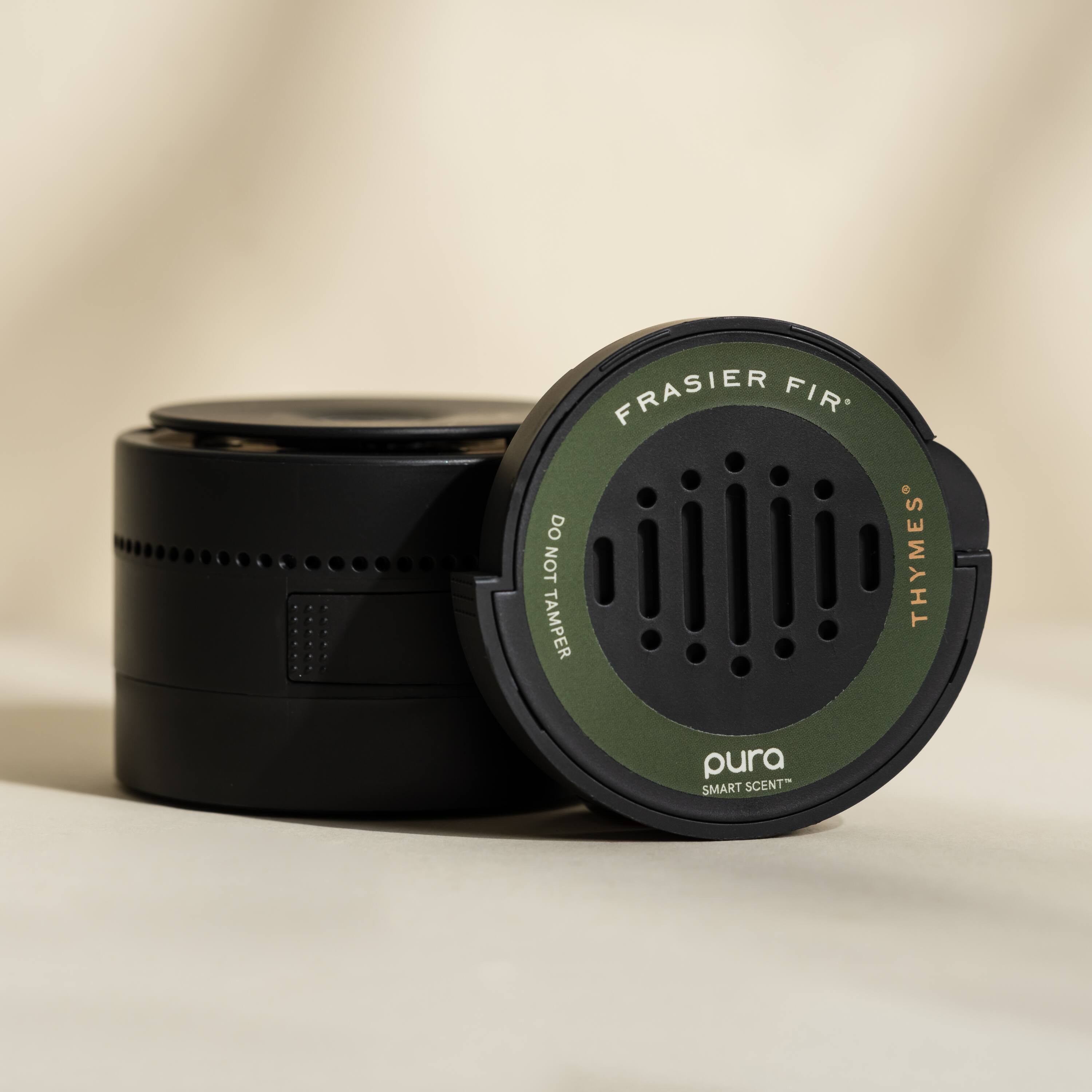 "Frasier Fir" is a brand name for a product that is designed to emit the scent of a pine forest. The product is made by the company "pura," and it is a smart scent device that can be used to enhance the ambiance of a space. The image shows the product sitting on a table, with the brand name and company name clearly visible. The product is designed to be used with aroma oils, and it is intended to provide a pleasant and refreshing scent to the environment.