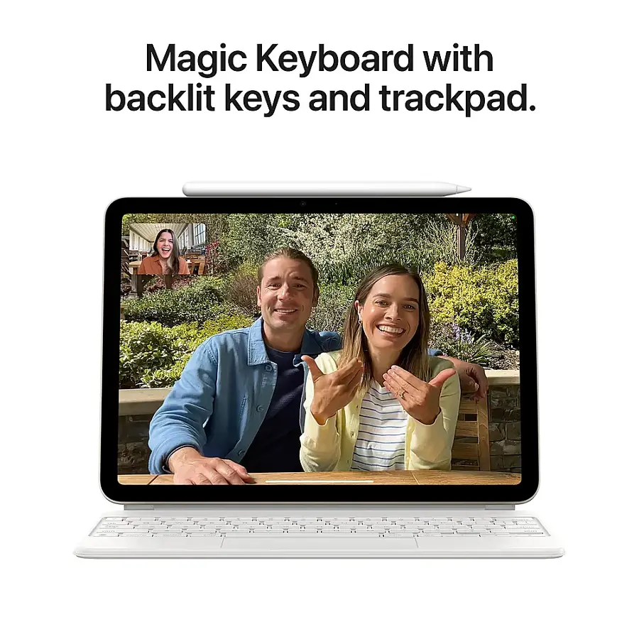 The image features a man and a woman sitting in front of a laptop computer. The laptop has a Magic Keyboard with backlit keys and trackpad, making it an attractive and functional device. The woman is smiling, and the man is holding her hand, suggesting a friendly and positive atmosphere. The laptop is placed on a dining table, which adds to the cozy and comfortable setting.