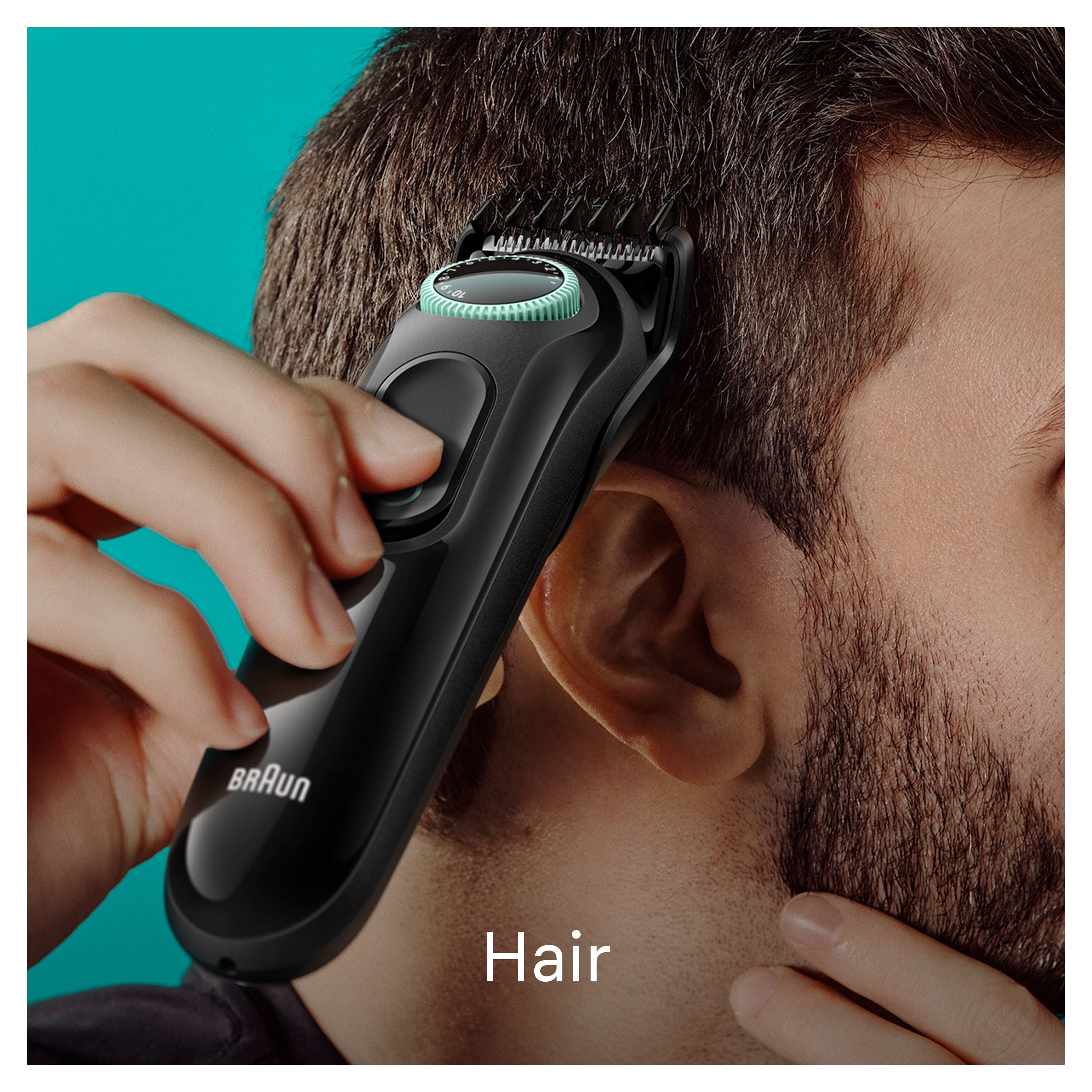 The image features a man holding a Braun hair trimmer to his ear. The trimmer is black and silver in color, and it appears to be a cordless electric trimmer. The man is using the trimmer to groom his hair, possibly trimming his sideburns or ear hair. The image is focused on the man and the trimmer, showcasing the close-up view of the grooming process.