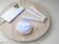 The image features a wooden tray with various items, including a cell phone, a toothbrush, and a tooth whitening device. The tooth whitening device is the most prominent item in the image, occupying a significant portion of the tray. The cell phone is placed next to the tooth whitening device, while the toothbrush is located towards the right side of the tray. The presence of these items suggests that the tray is being used as a storage or display area for personal care and hygiene products.
