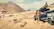 "The man and woman are standing next to a truck in a field."