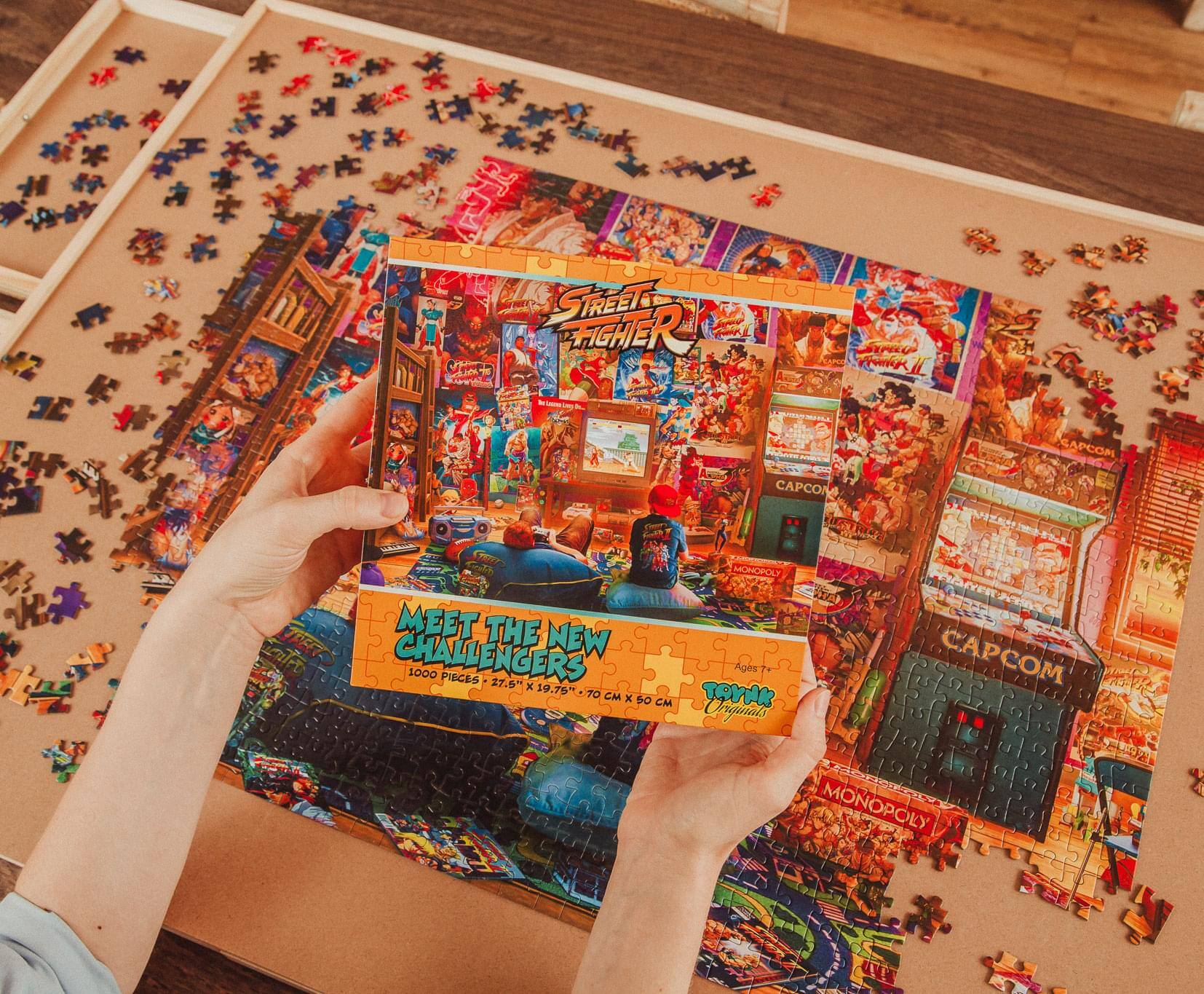 Sure, here is the corrected and grouped text from the image:

---

**Top Left Box:**
- STREET FIGHTER
- MEET THE NEW CHALLENGERS
- 1000 PIECES
- 27.5" x 19.75" TOYAKO
- CM x CM

**Top Right Box:**
- CAPCOM
- MONOPOLY
- CM x 50 CM

**Bottom Left Box:**
- TOYAKO
- Originals

**Bottom Right Box:**
- MONOPOLY

---

This text is organized based on the visible sections of the puzzle boxes in the image.