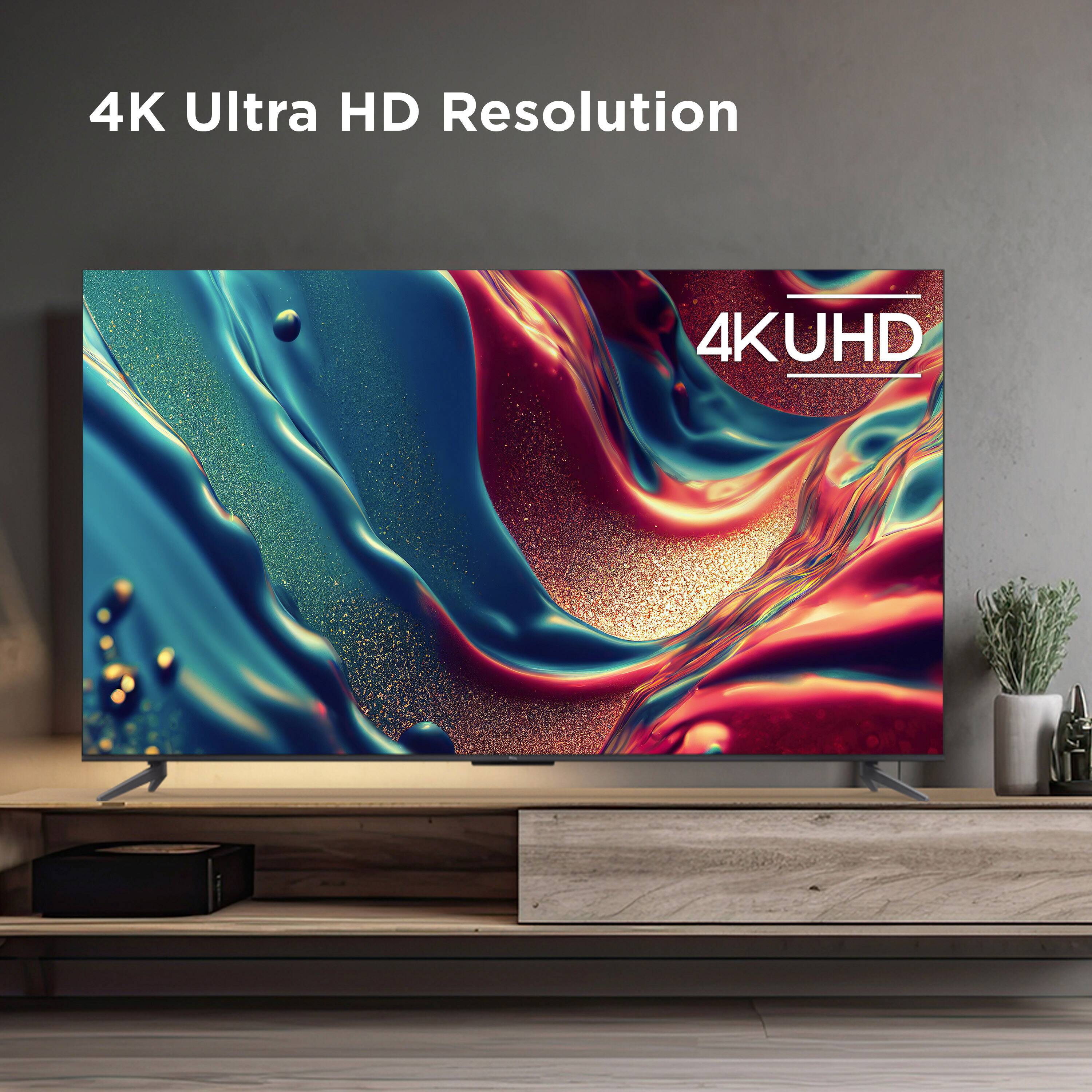 The image features a large flat screen television with a 4K Ultra HD resolution. The TV is placed on a wooden stand, and it is the main focus of the scene. The television screen displays a vibrant and colorful image, showcasing the high-quality resolution of the 4KUHD display. The image emphasizes the sharpness and clarity of the screen, making it an attractive choice for those looking to upgrade their viewing experience.