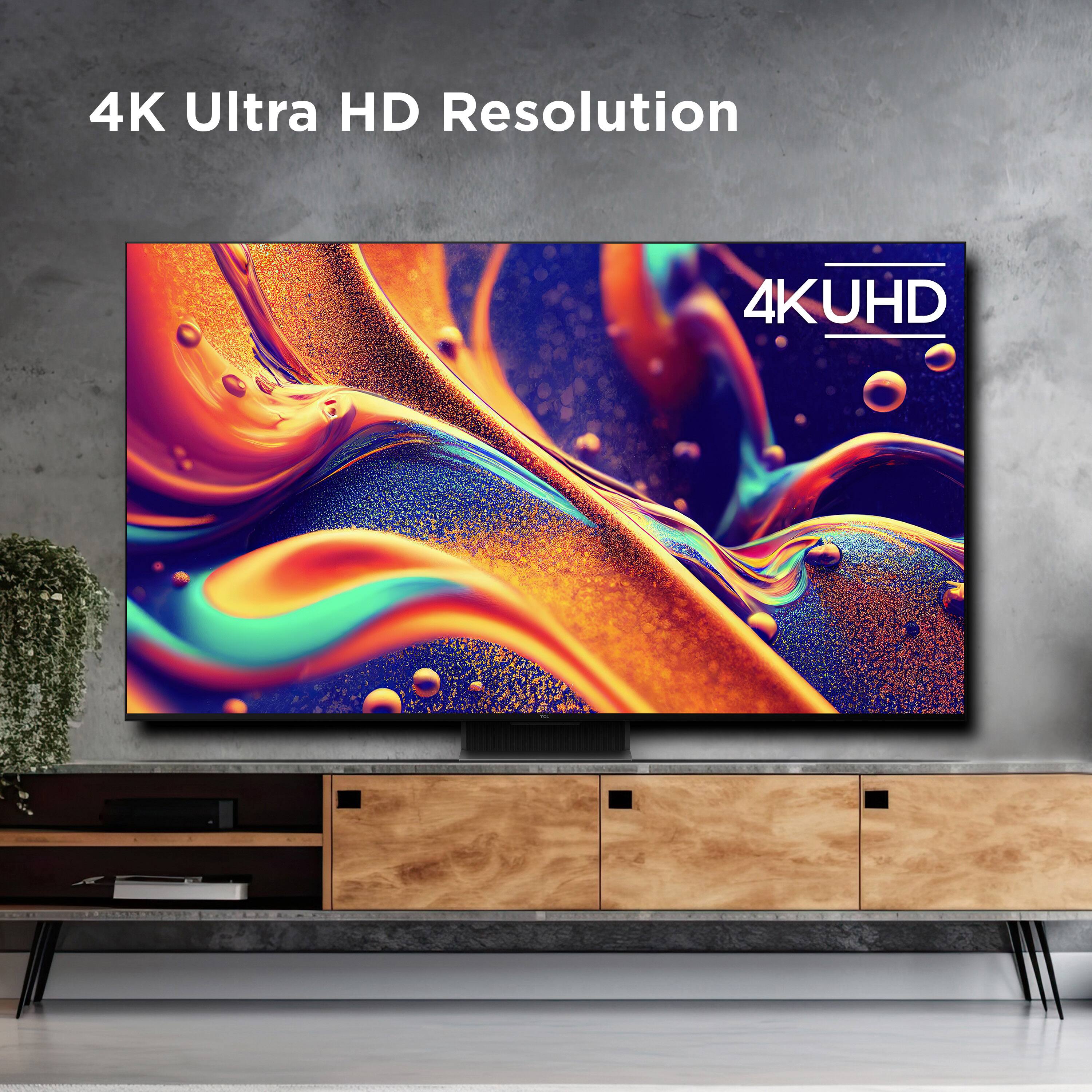 The image features a large flat screen television with a 4K Ultra HD resolution. The TV is mounted on a wall, and it is accompanied by a wooden entertainment center. The television screen displays a colorful and dynamic image, showcasing its high-quality resolution.