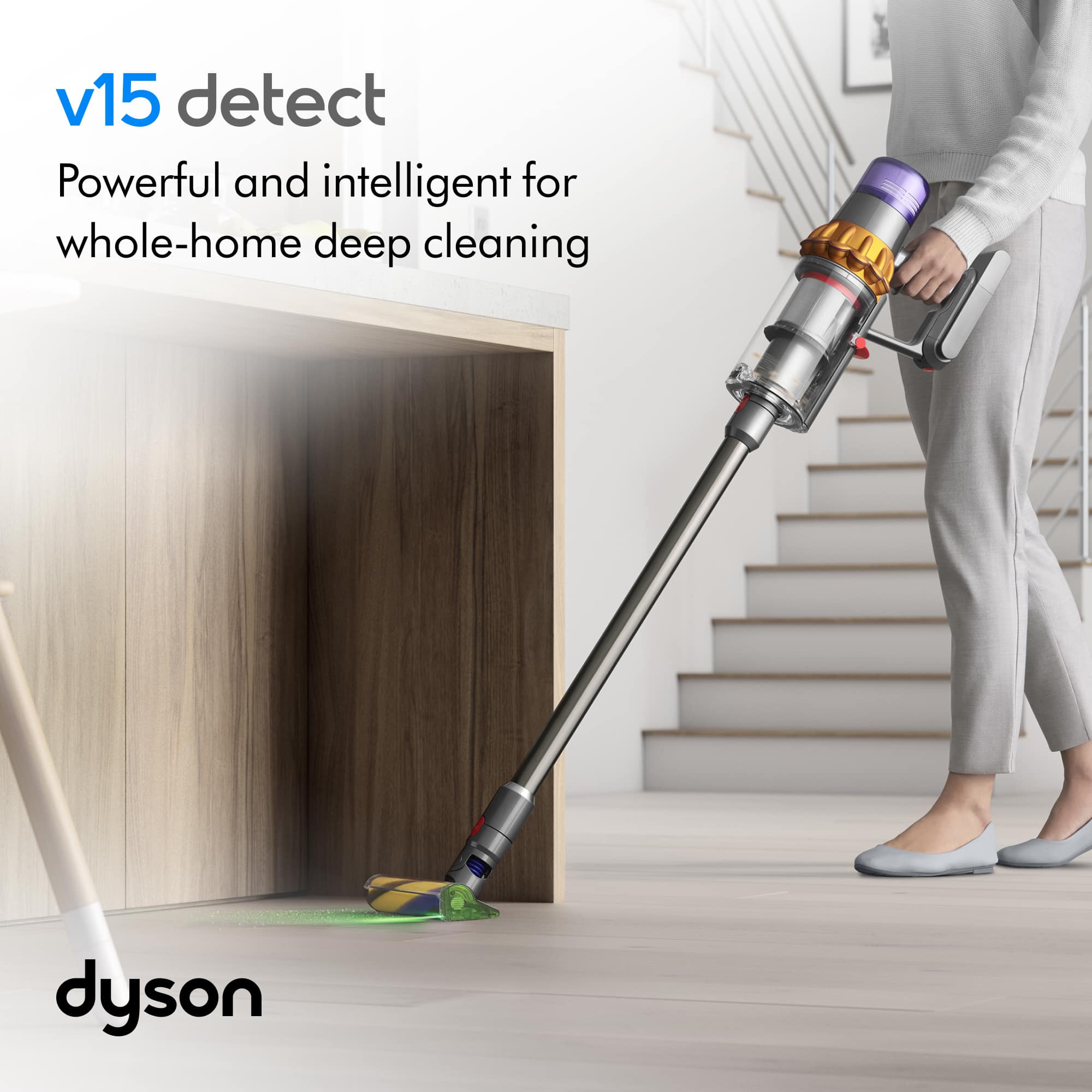 The image features a woman using a Dyson handheld vacuum cleaner to clean a wooden floor. The vacuum is equipped with a powerful and intelligent system, making it suitable for whole-home deep cleaning. The woman is holding the vacuum and actively cleaning the floor, showcasing the effectiveness of the device.