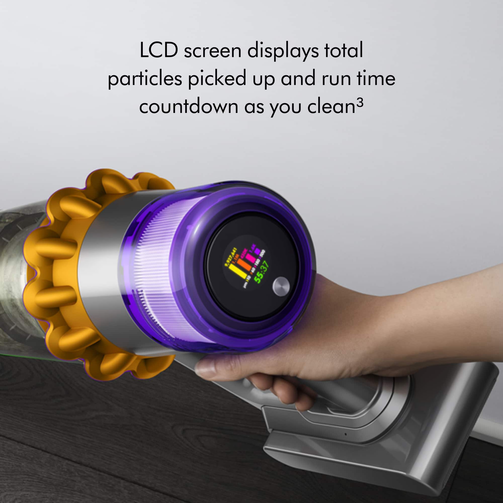 The image features a handheld vacuum cleaner with a purple and orange design. The vacuum has a large LCD screen that displays the total particles picked up and the run time countdown as you clean. The person in the image is holding the vacuum, showcasing its features and functionality.