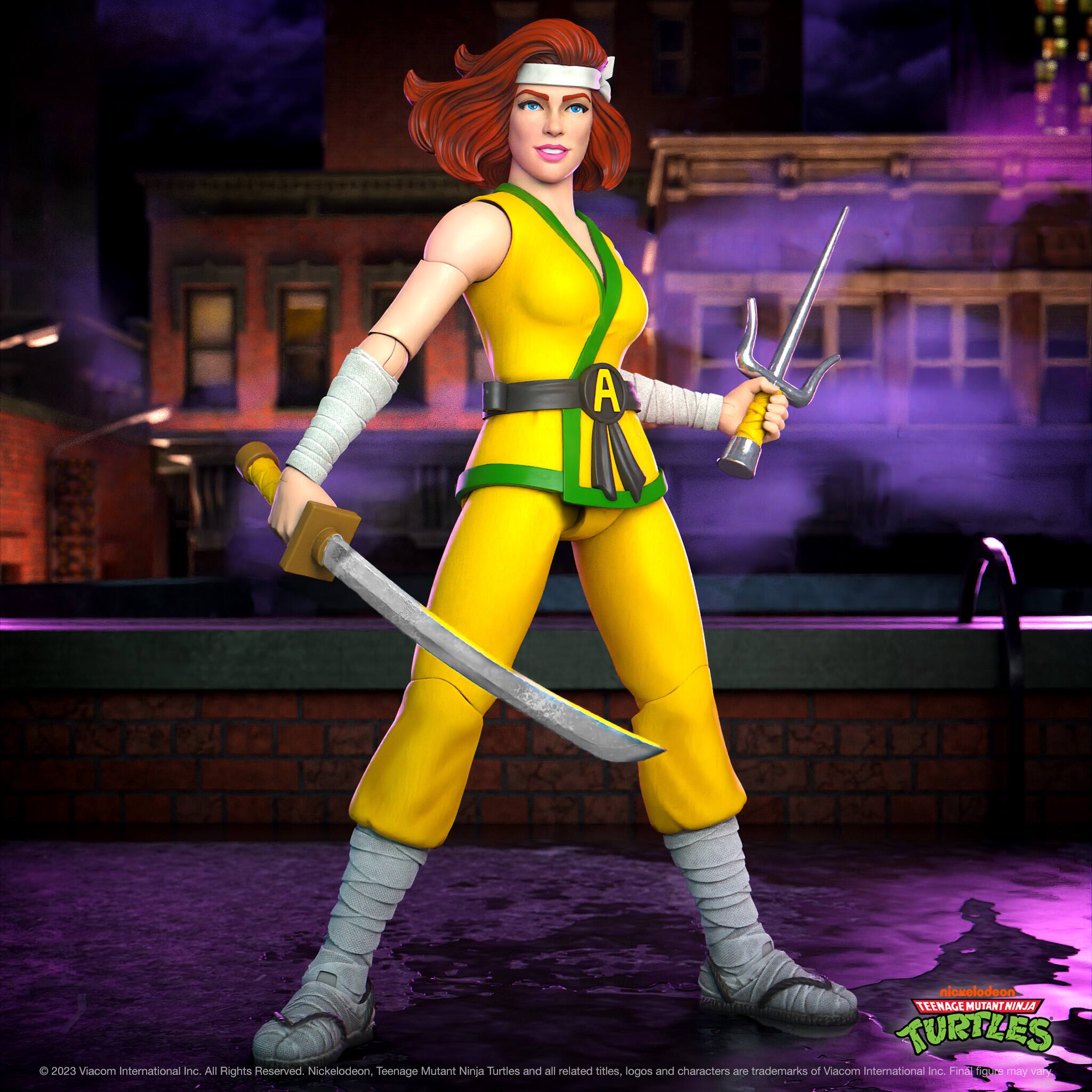 The image features a female action figure dressed in a yellow outfit, holding a sword and a bow. She is standing on a brick surface, possibly a sidewalk. The action figure is part of the Teenage Mutant Ninja Turtles franchise, which is owned by Viacom International Inc.