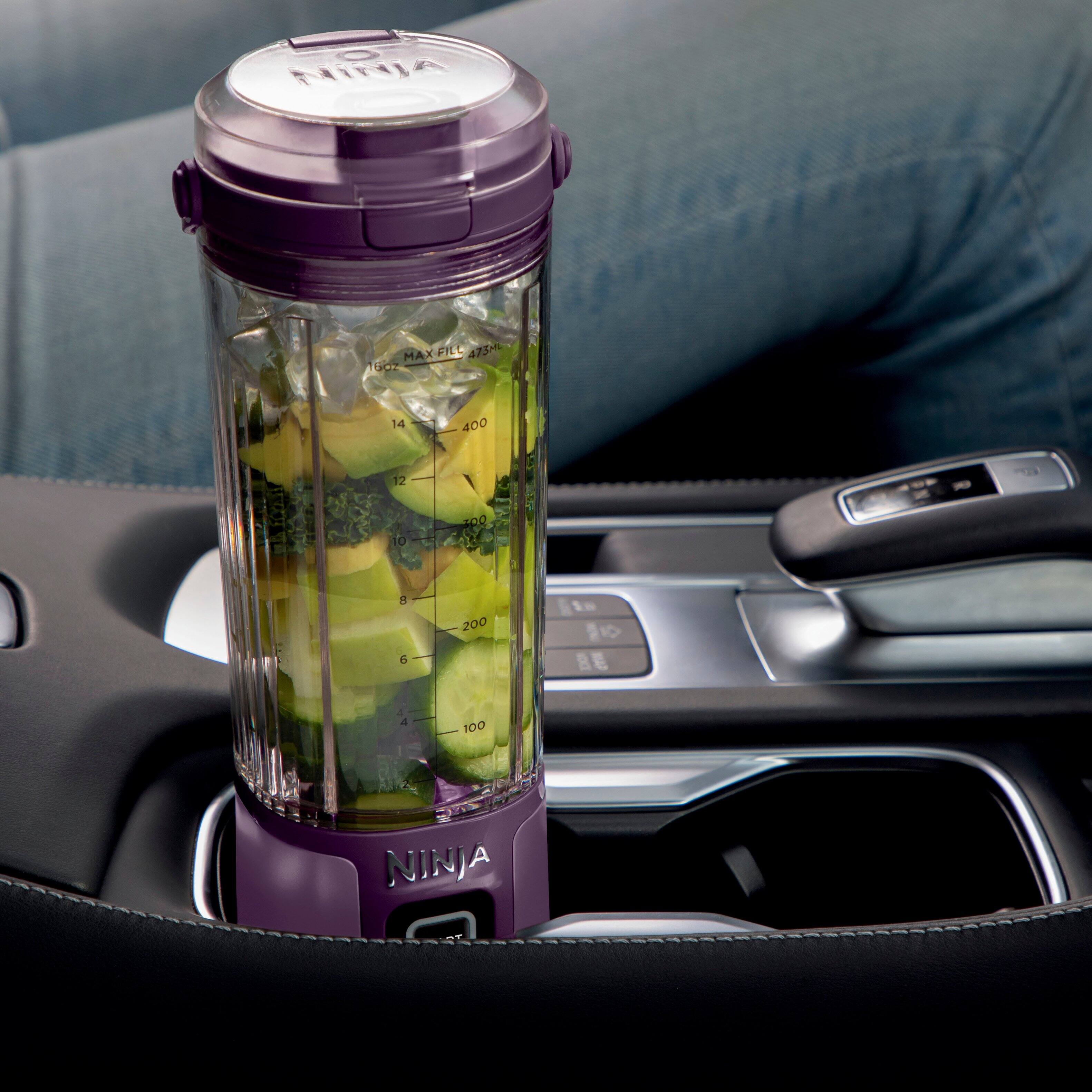 The image features a Ninja cup holder that is placed in a car cup holder. The cup holder is filled with cut-up vegetables, making it a convenient and portable option for travel and on-the-go meals. The cup holder is designed to fit comfortably in car cup holders, providing a practical solution for those who want to enjoy a healthy snack while on the road.