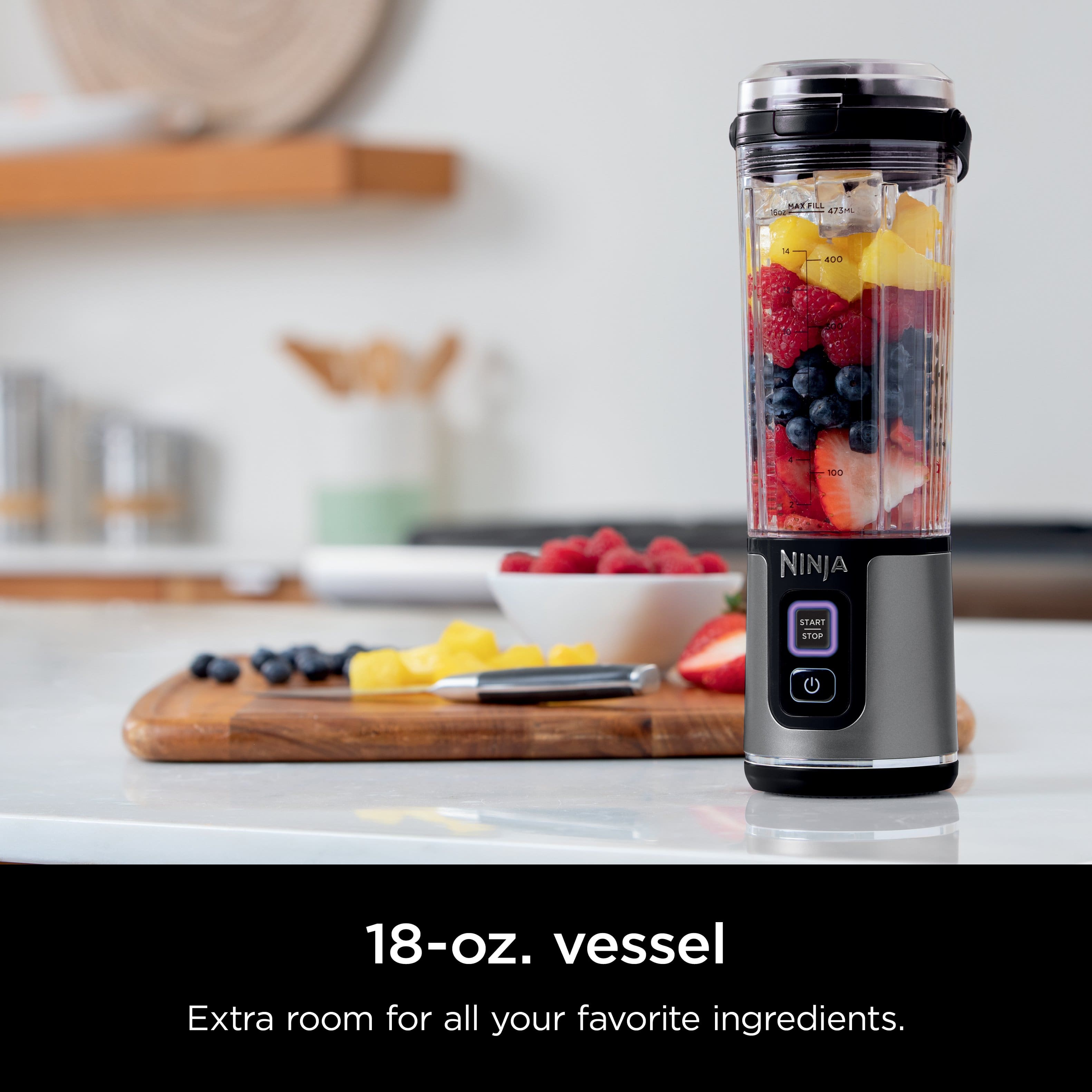 The image features a Ninja blender with a bowl of fruit on a counter. The blender is filled with fruit, including strawberries, blueberries, and bananas. The blender is placed on a table, and there is a spoon nearby. The advertisement suggests that the Ninja blender has an extra 18-oz. vessel, providing ample space for all your favorite ingredients.