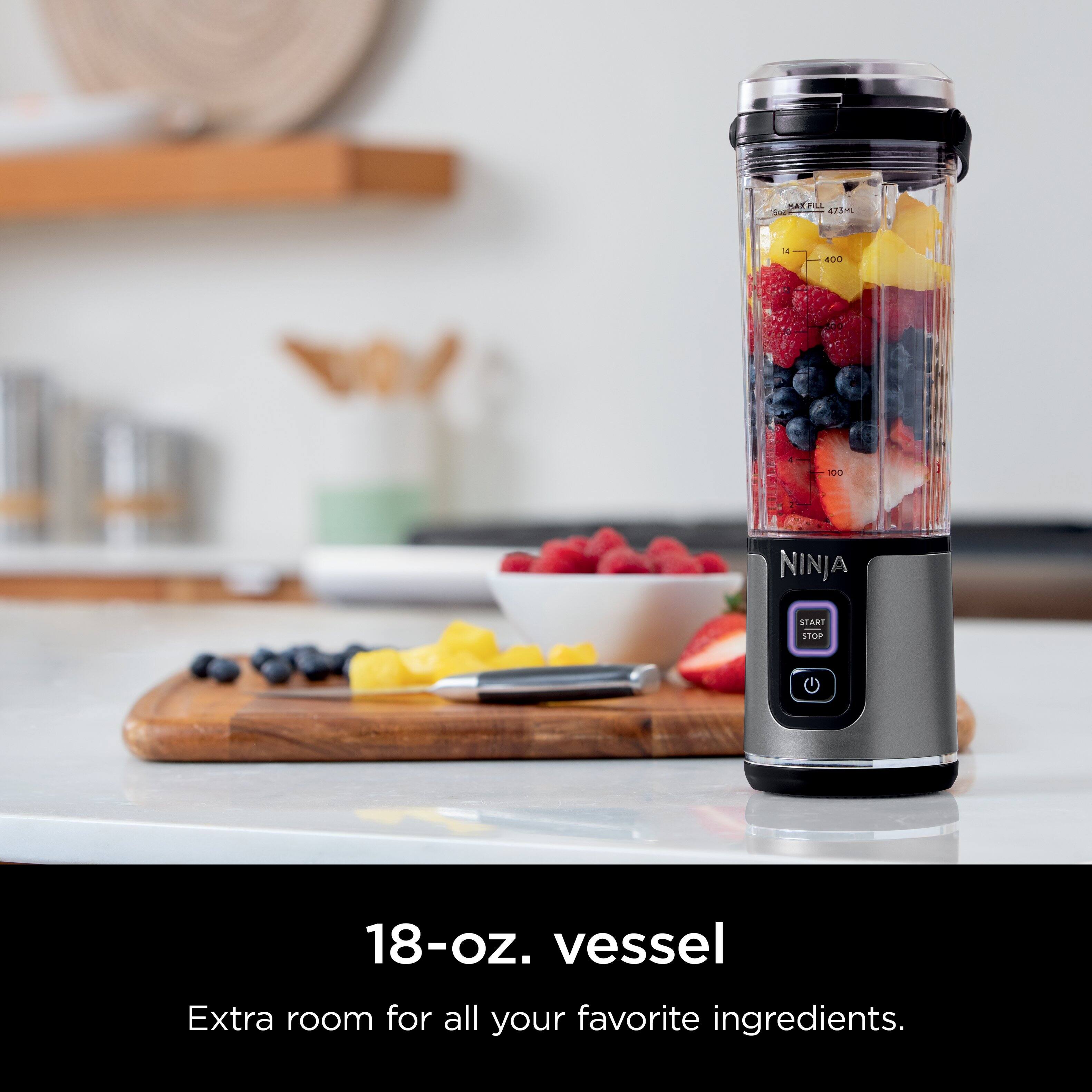 The image features a Ninja blender with a bowl of fruit on a counter. The blender is filled with fruit, including strawberries, blueberries, and bananas. The blender is placed on a table, and there is a spoon nearby. The advertisement suggests that the Ninja blender has an extra 18-oz. vessel, providing ample space for all your favorite ingredients.
