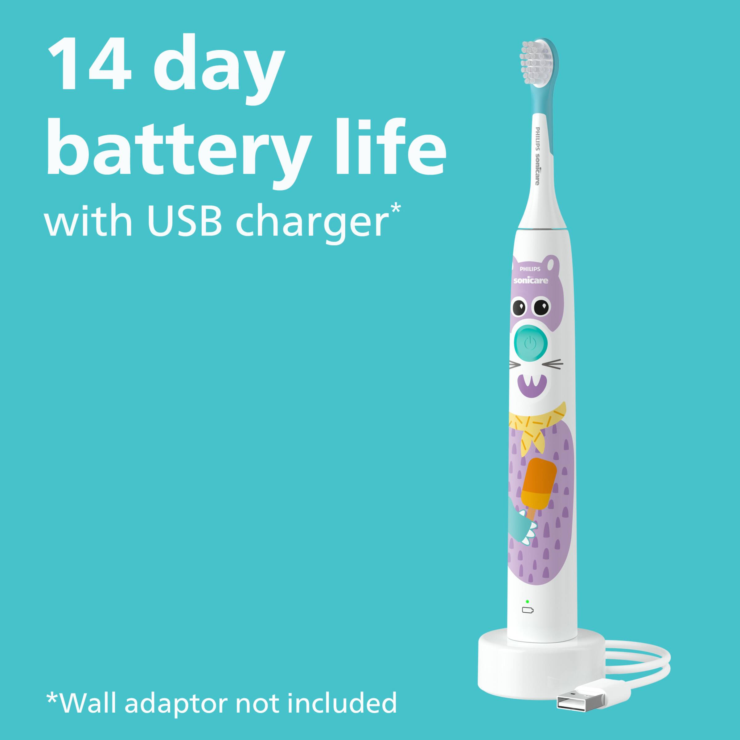 The image features an electric toothbrush with a cat design on it. The toothbrush has a USB charger and offers a 14-day battery life. The toothbrush is white and purple, and it is designed to be used with a wall adaptor, which is not included in the package.