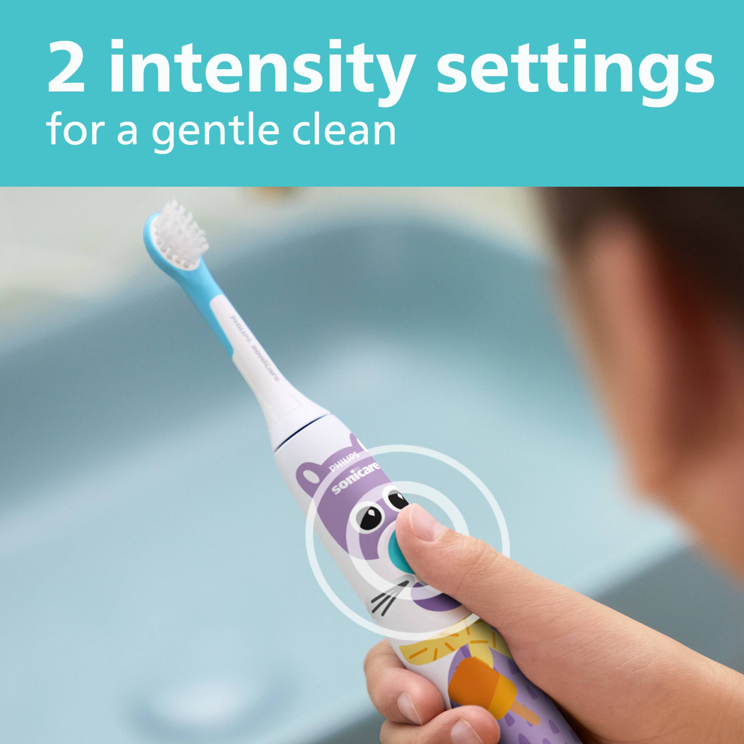 The image features a person holding a toothbrush with a cat on it, which is an electric toothbrush. The toothbrush has two intensity settings for a gentle clean, making it suitable for sensitive teeth and gums. The cat on the toothbrush adds a playful touch to the design, making it appealing to users of all ages.