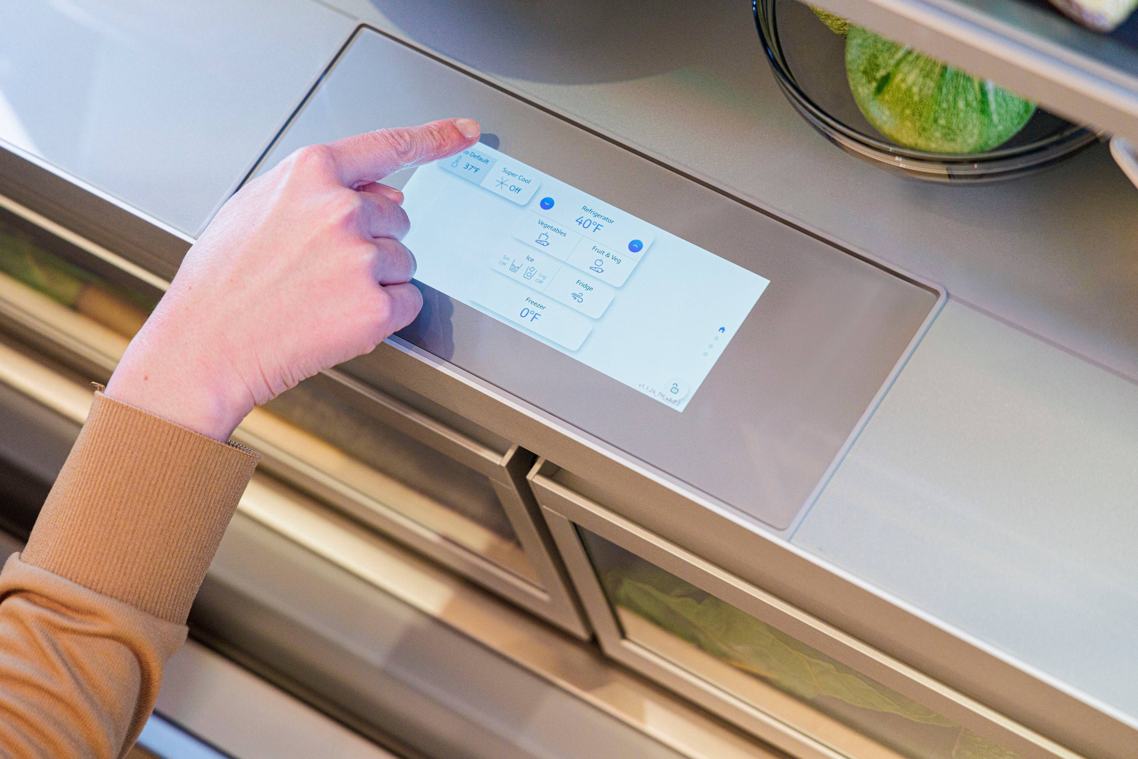 The text on the image reads: "Default 37Y Super * Coo Off 40F Refrigerator Drgetables Frud * Fridge Freezer 0F 2 1.2 m". This text appears to be a combination of instructions and settings for a refrigerator, with the main focus being on the temperature settings. The person in the image is pointing at the digital display, possibly indicating that they are adjusting the settings or checking the current temperature.