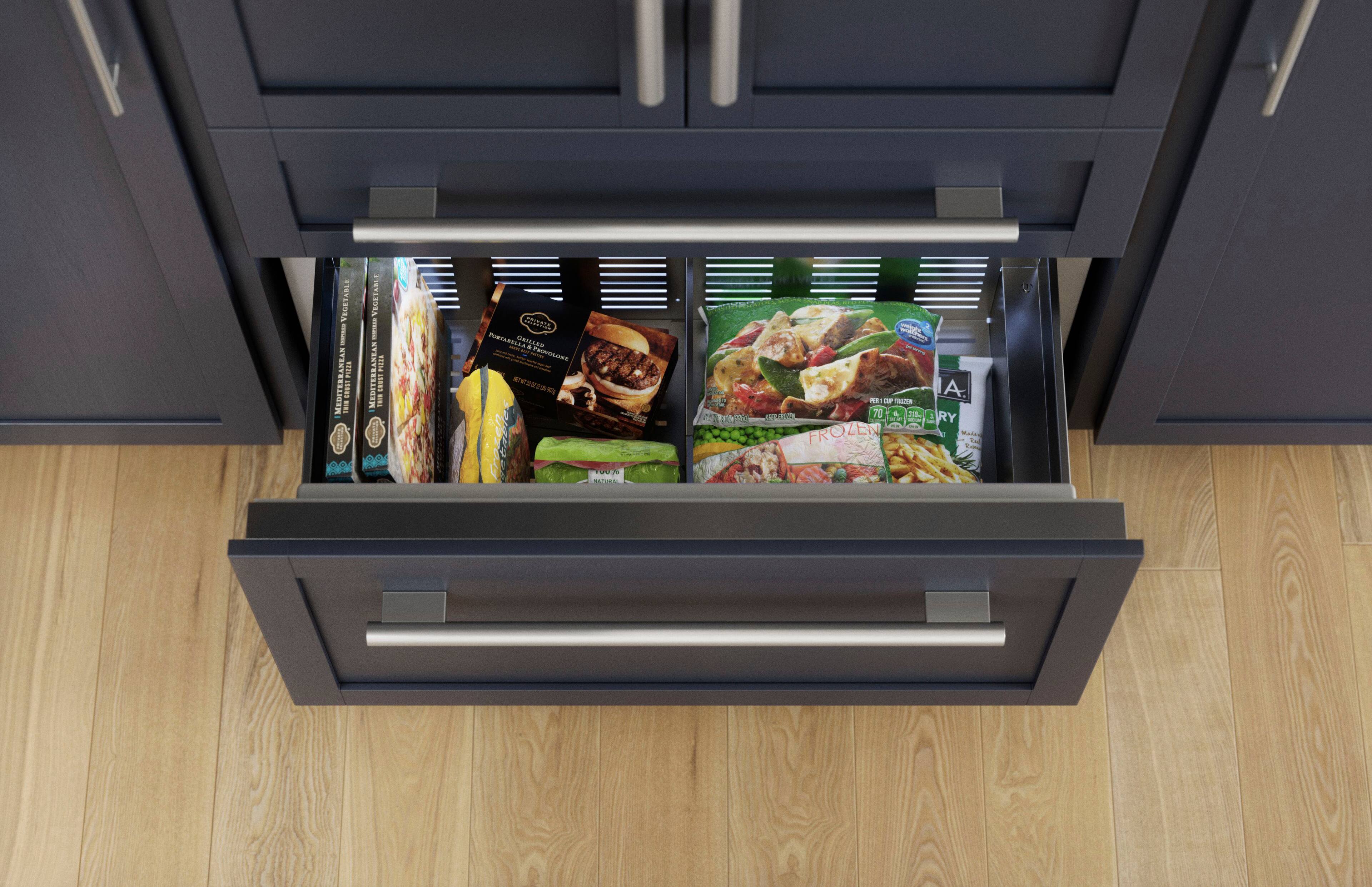 The image shows a kitchen with a drawer open, revealing a variety of food items inside. There are several frozen pizzas, including one with a Mediterranean topping, and a few sandwiches. Additionally, there are some vegetables and a couple of books placed in the drawer. The drawer is filled with a mix of food items and kitchen essentials, making it a convenient storage space for everyday use.