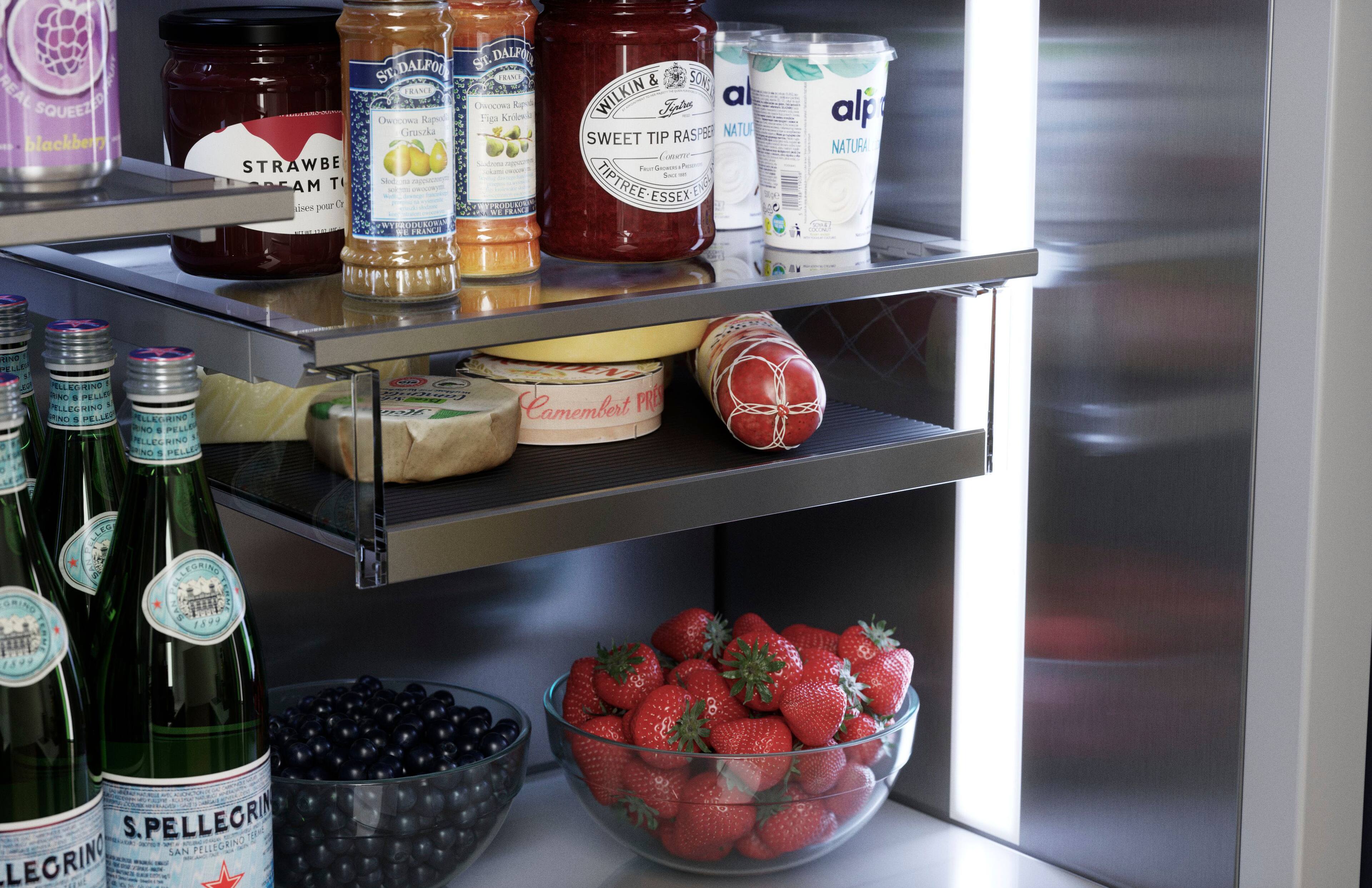 The image shows a refrigerator with a variety of food items and drinks. There are several bottles of wine and other beverages, including a bottle of Pelligrino. The refrigerator also contains a bowl of strawberries and a bowl of blueberries. Additionally, there are jars of jam and jelly, as well as a container of yogurt. The refrigerator is well-stocked with a diverse selection of food and drinks.