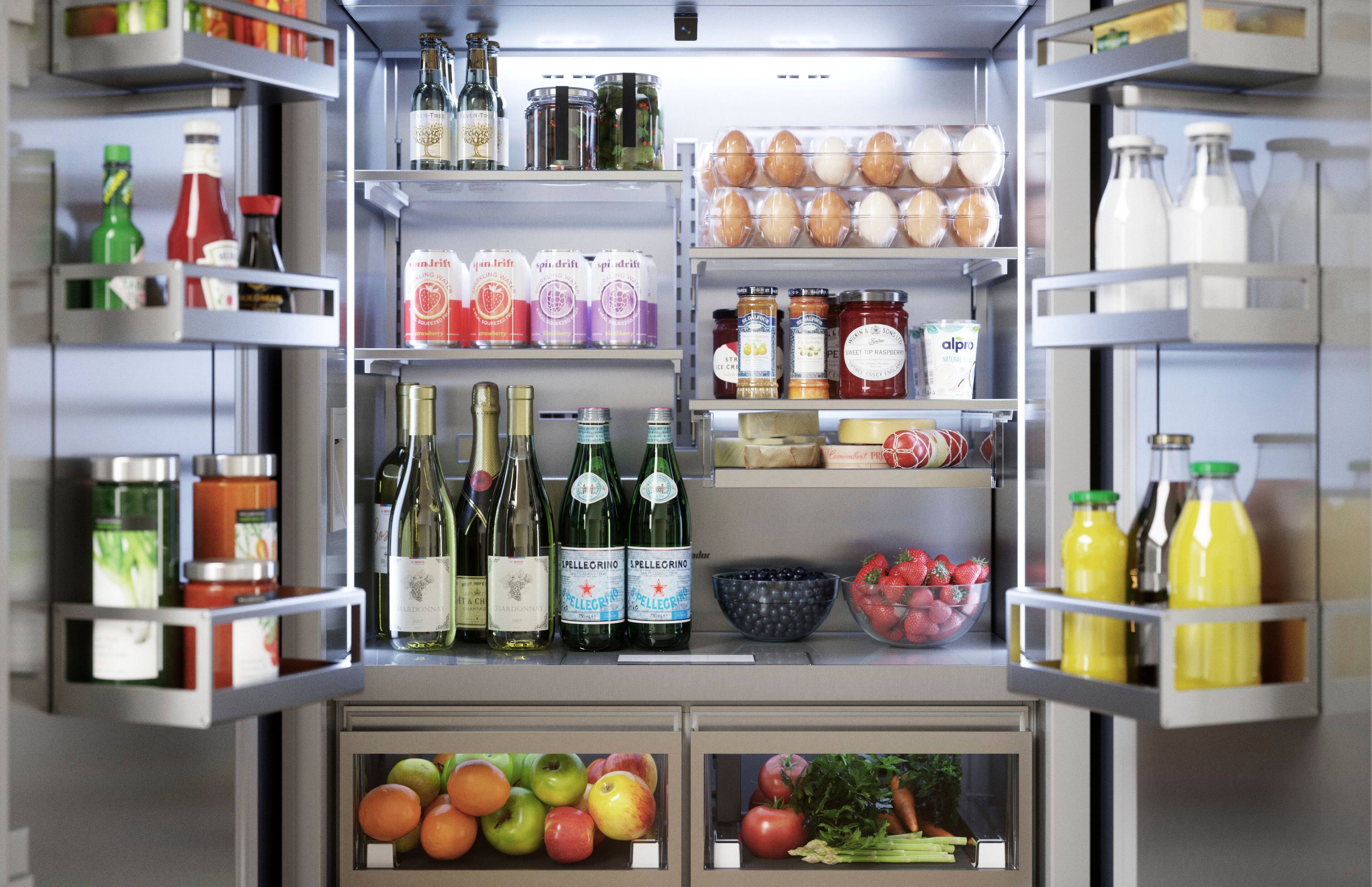 The image features a refrigerator filled with various food items and drinks. The refrigerator has a section dedicated to fruits, with apples and oranges visible. There are also several bottles of wine and other beverages stored in the refrigerator. The refrigerator is well-stocked, providing a variety of options for snacking and meal preparation.