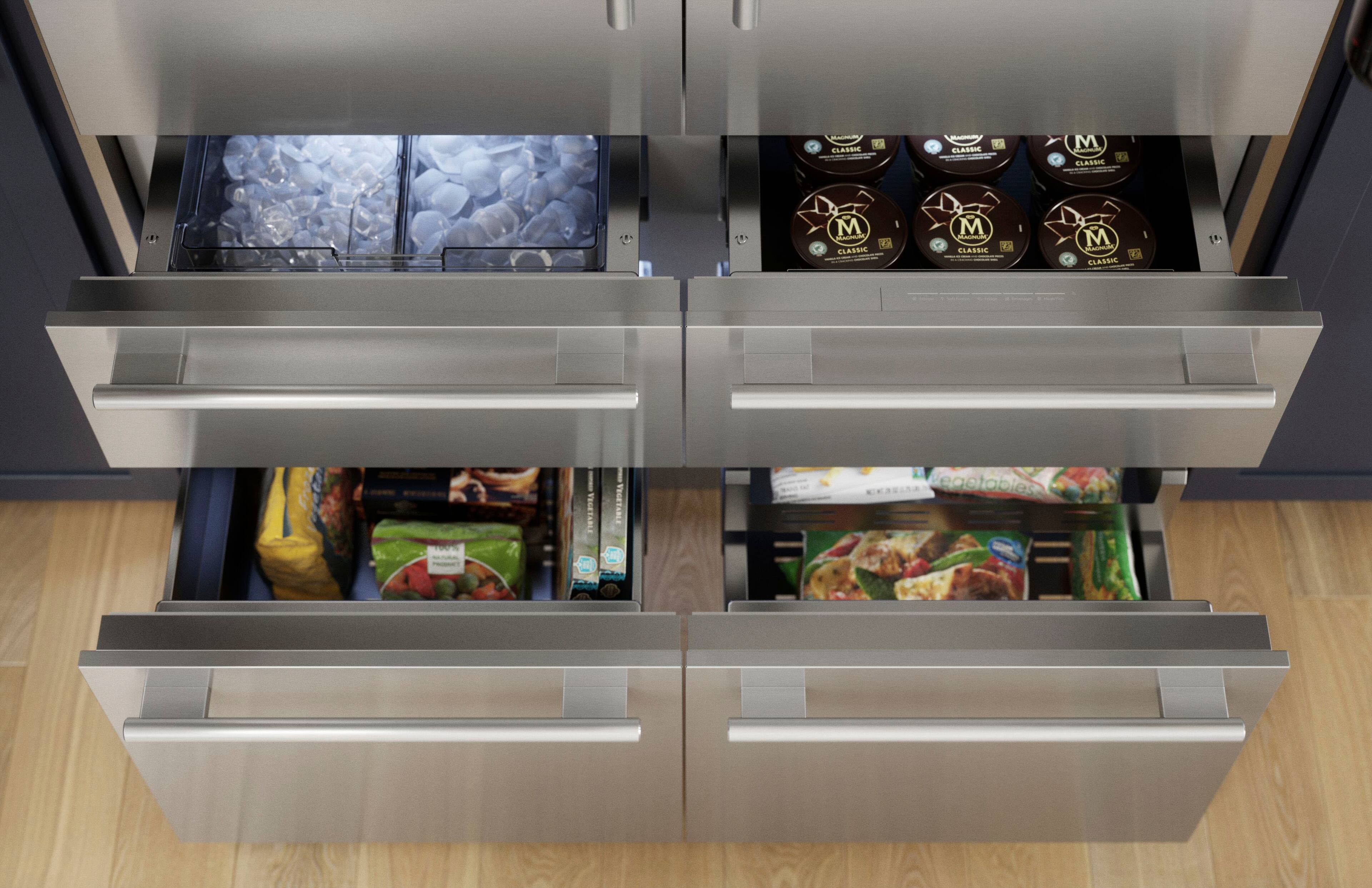 The image shows a refrigerator with a drawer open, revealing a variety of food items. There are several bottles, including a bottle of wine, and a cake placed in the drawer. The refrigerator also contains a drawer full of vegetables, which includes carrots and broccoli. Additionally, there are two bowls, one of which is placed on top of the refrigerator. The refrigerator is stocked with a diverse selection of food items, making it a convenient and well-organized space for storing and accessing food.
