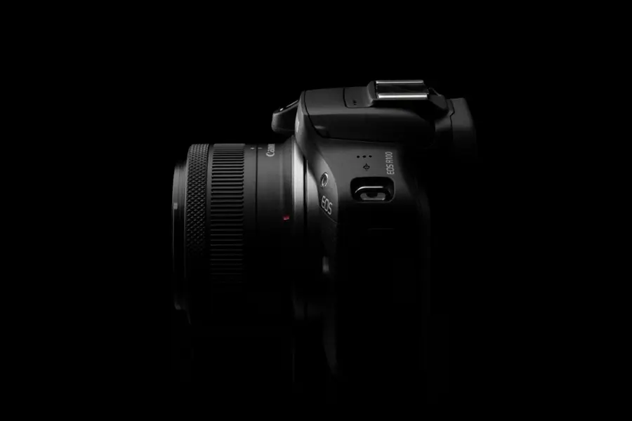 The image features a black digital camera, which is a Canon EOS 5D Mark III. The camera is positioned in the center of the image, with a close-up view that highlights its details. The camera is surrounded by a dark background, which further emphasizes its presence in the scene.