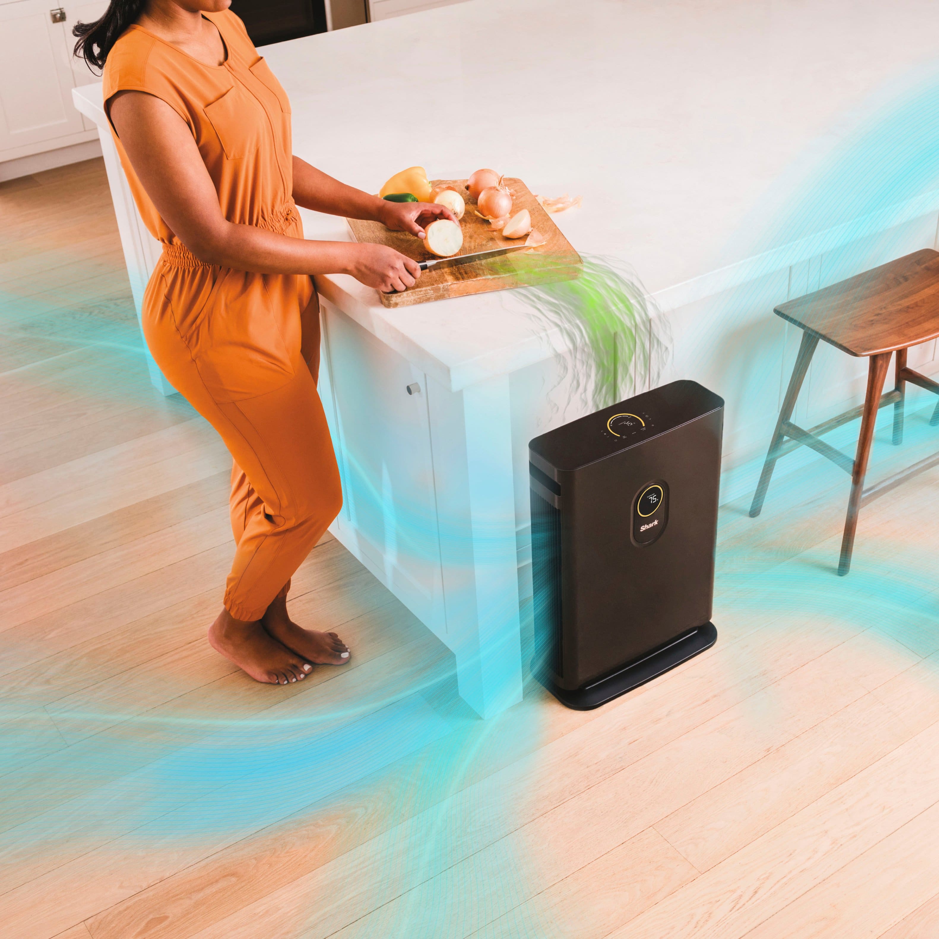 The image features a woman standing in a kitchen, holding a plate of vegetables. There is a child nearby, and a dining table is visible in the scene. The focus of the image is on the advanced odor protection, which is an odor guard on the filter that protects against household odors from cooking, cleaning products, and more. The image emphasizes the importance of maintaining a clean and odor-free environment in the home.