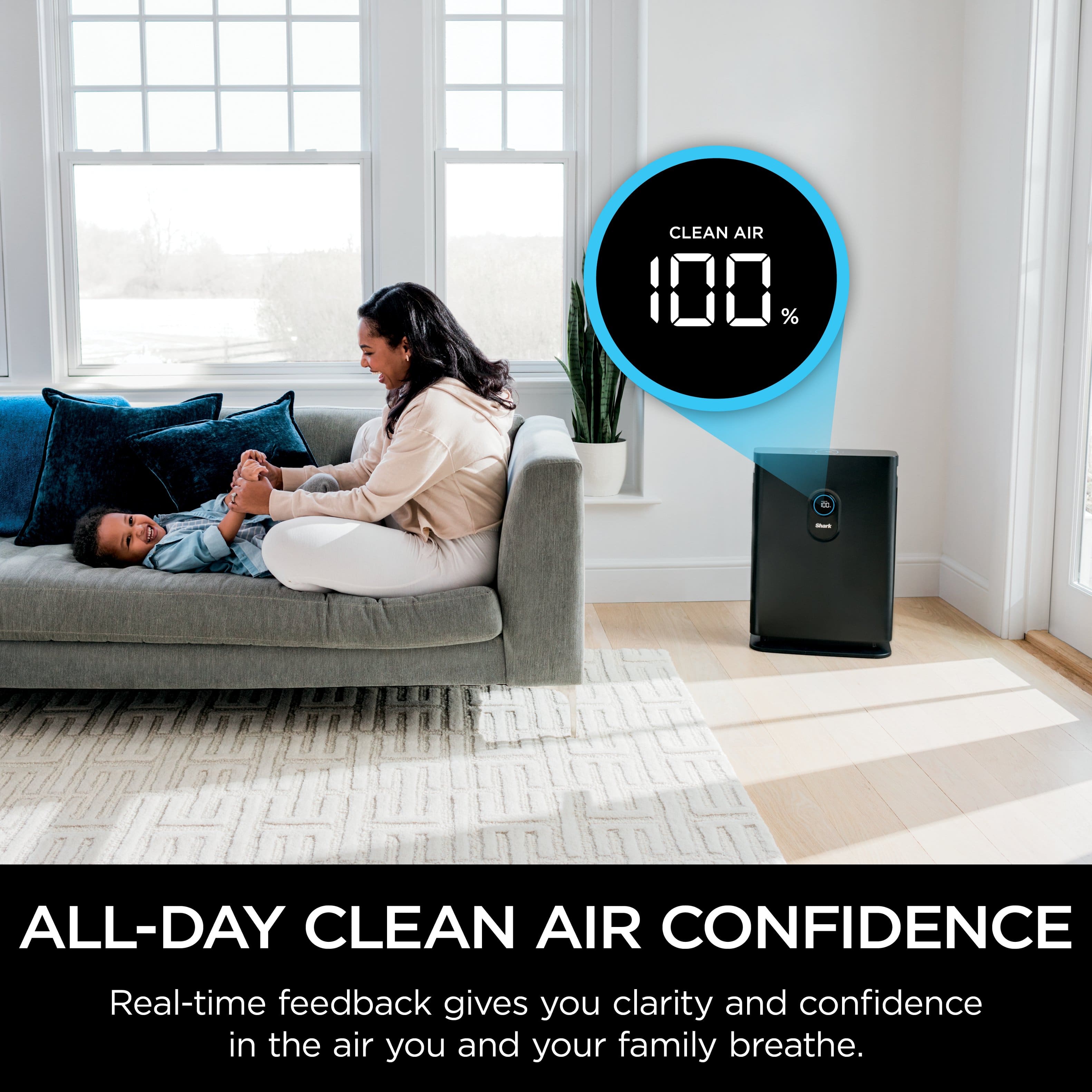 The image features a woman sitting on a couch with a child, both of them smiling. There is a potted plant nearby, and a couch can be seen in the background. The main focus of the image is a clean air machine, which is placed in the room. The machine is advertised as providing 100% clean air, giving users confidence in the air they breathe. The image is likely promoting the benefits of using the clean air machine, emphasizing its effectiveness in maintaining a healthy indoor environment.