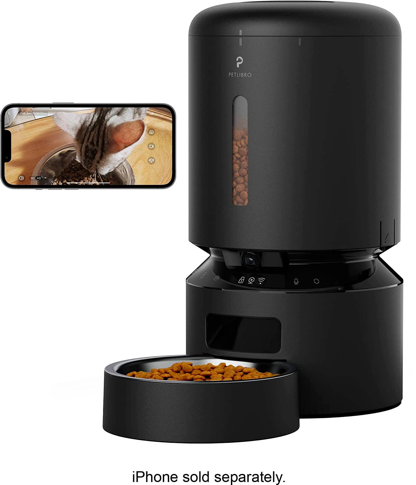 The image features a pet feeder, specifically a cat feeder, with a bowl of food inside. The feeder is placed next to a cell phone, which is also displayed in the image. The text "PETLIBRO D D  iPhone sold separately" is present in the image, indicating that the iPhone is not included with the pet feeder and must be purchased separately.
