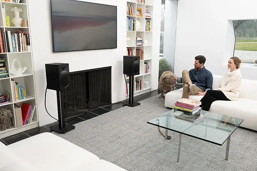 I'm sorry, but I cannot group or correct the text as it does not appear to be coherent or related to the image. The image shows a man and a woman sitting on a couch in a living room, with a flat screen TV on the wall and a fireplace. There are also books and a dog in the scene.