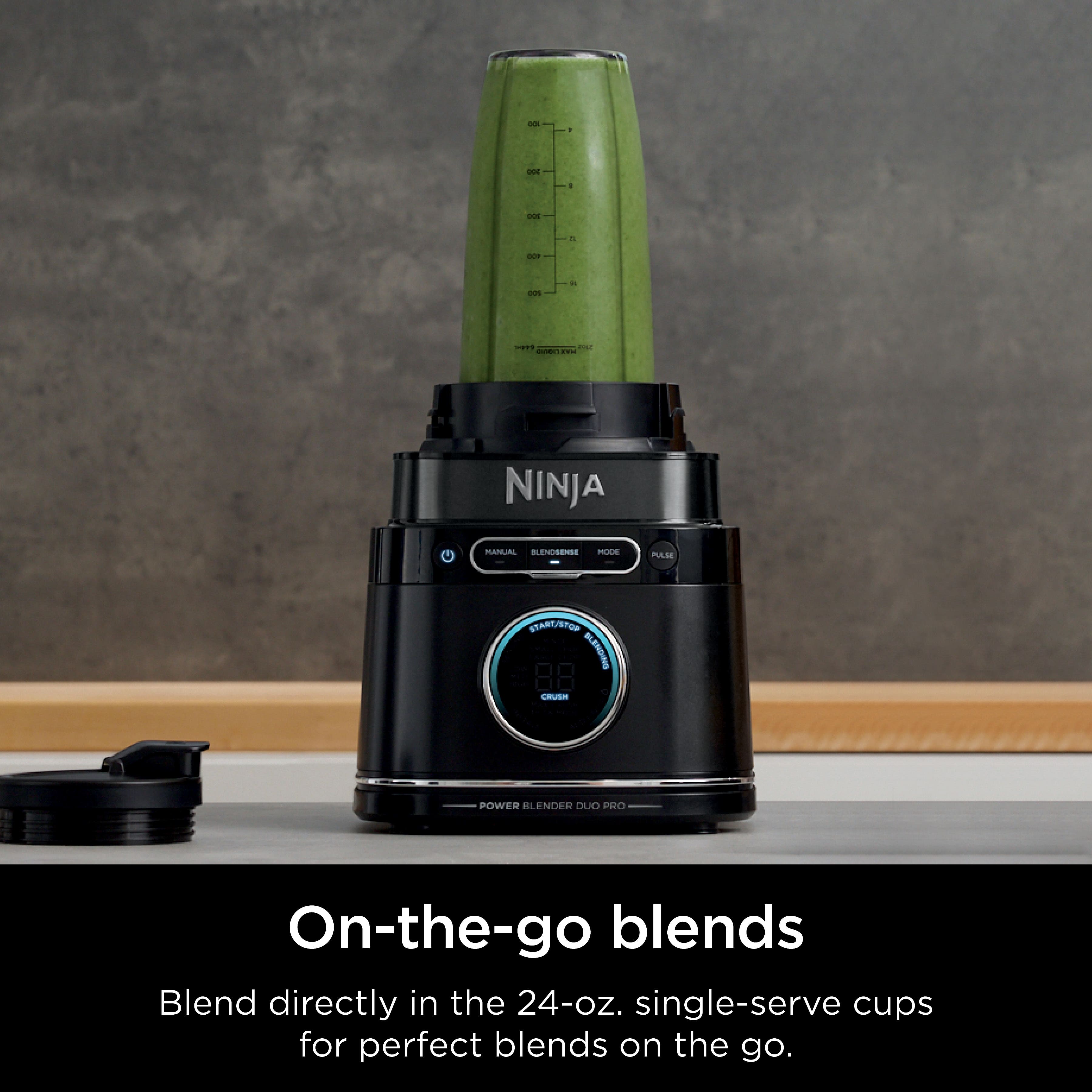 The image features a Ninja blender with a green liquid inside, sitting on a counter. The blender is designed for on-the-go blends, allowing users to blend directly in the 24-oz. single-serve cups for perfect blends while on the go. The blender is compact and portable, making it a convenient option for those who want to enjoy their blended drinks without needing to carry a separate cup.