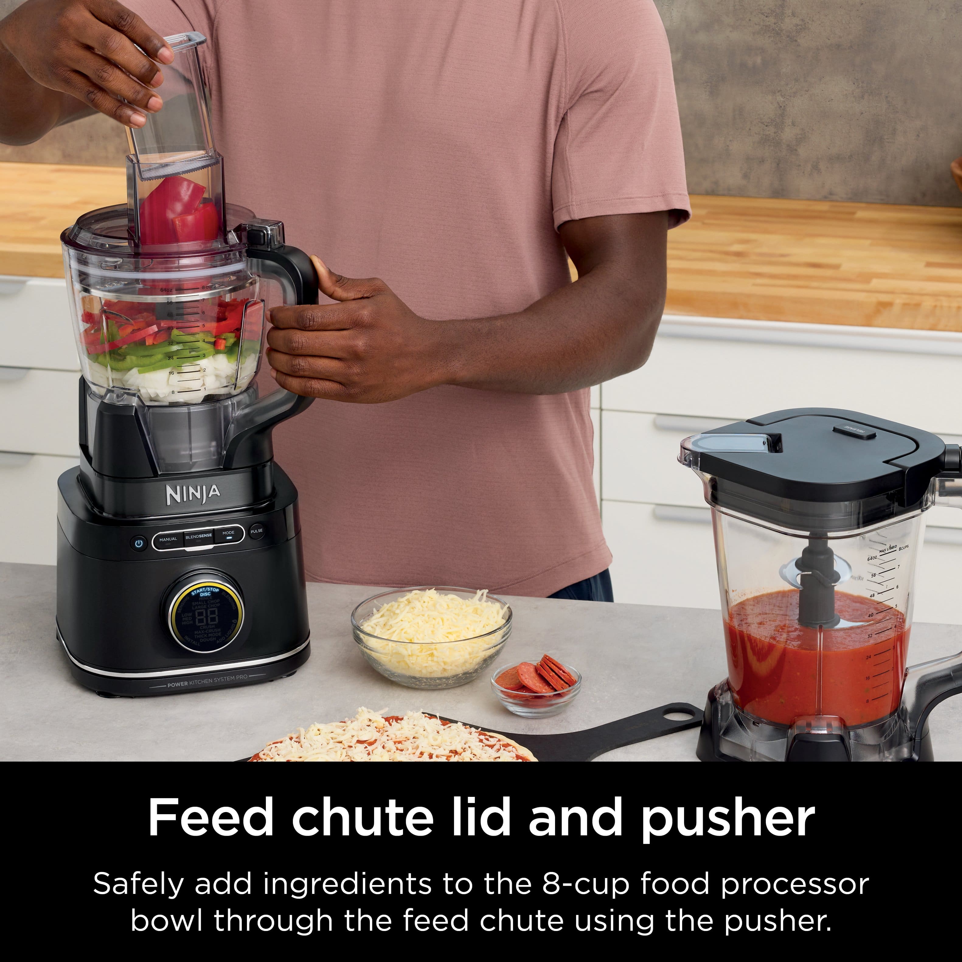 The image shows a man preparing food in a kitchen, using a Ninja food processor. He is adding ingredients to the food processor bowl through the feed chute, which is a safe and convenient way to incorporate ingredients into the processor. The feed chute lid and pusher are essential components of the food processor, ensuring that the ingredients are added safely and efficiently.