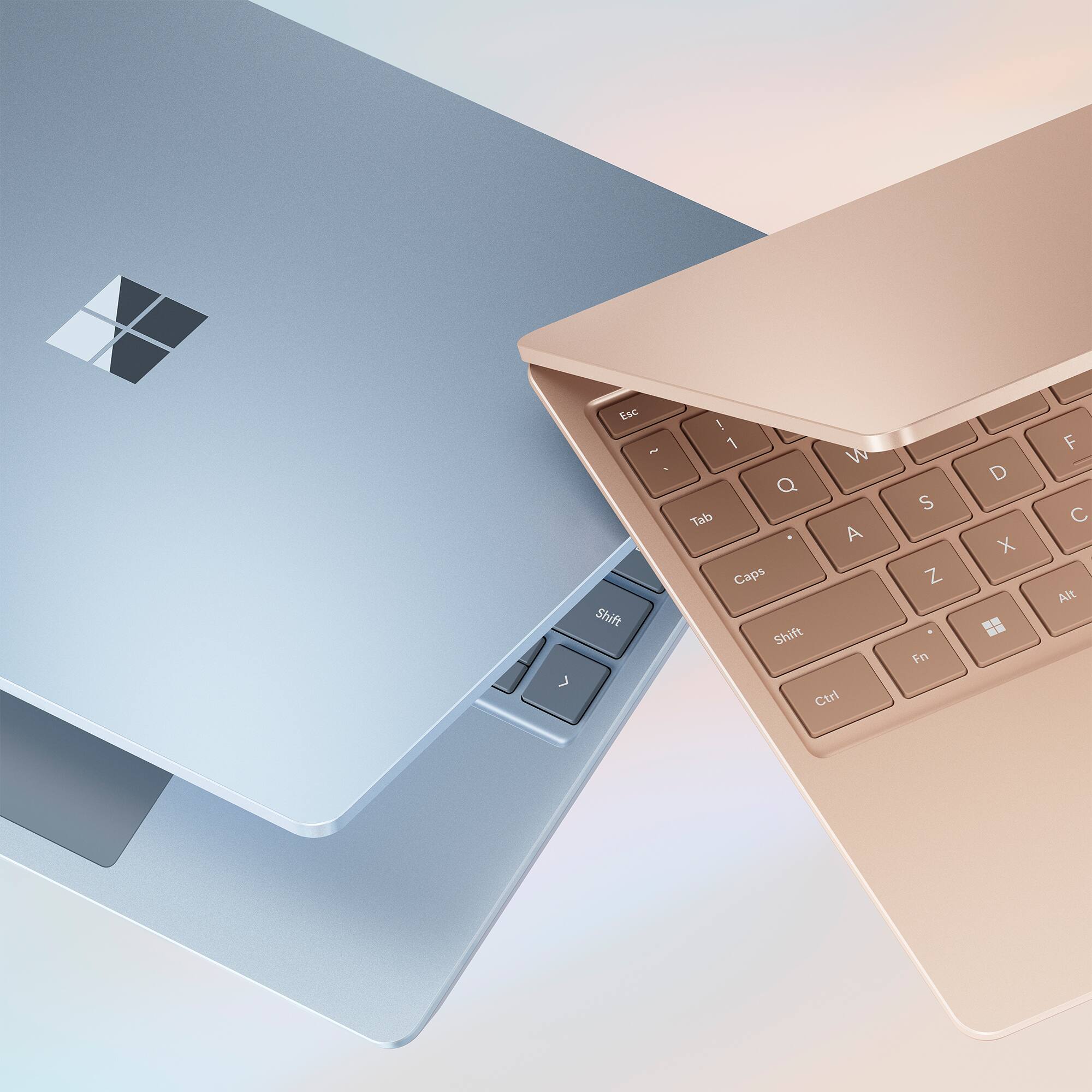 The image features two laptop computers, one with a silver keyboard and the other with a gold keyboard. The silver keyboard has the letters "Esc" and "Tab" visible, while the gold keyboard has the letters "Ctrl" and "Shift" visible. The two keyboards are placed side by side, showcasing their differences in color and design.