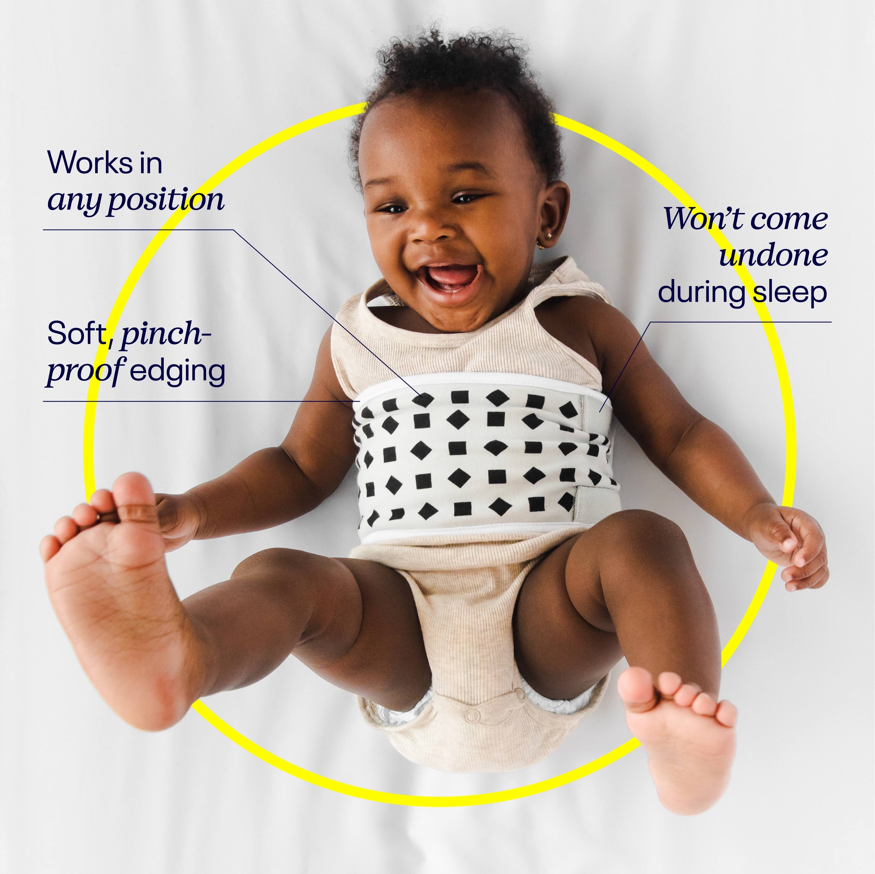 The image features a baby wearing a white and black outfit, lying on a bed. The baby is smiling and appears to be happy. The image is labeled with the text "Baby Monitor," which suggests that it is a device used to monitor the baby's safety and well-being while they sleep. The monitor is designed to work in any position, ensuring that it can be used effectively regardless of how the baby is lying down. The soft, pinch-proof edging provides a safe and comfortable environment for the baby, while the monitor won't come undone during sleep, ensuring that it remains securely in place.