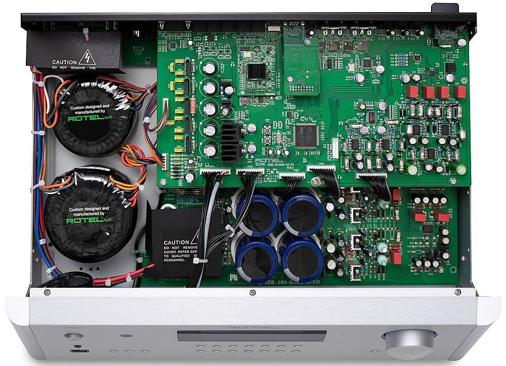 The image features a circuit board with various electronic components, including a power supply and a transformer. The board is custom designed and manufactured by Rotel. The components are connected with wires, and there are two fans visible in the image. The circuit board is a part of a device that requires qualified personnel to operate and maintain it.