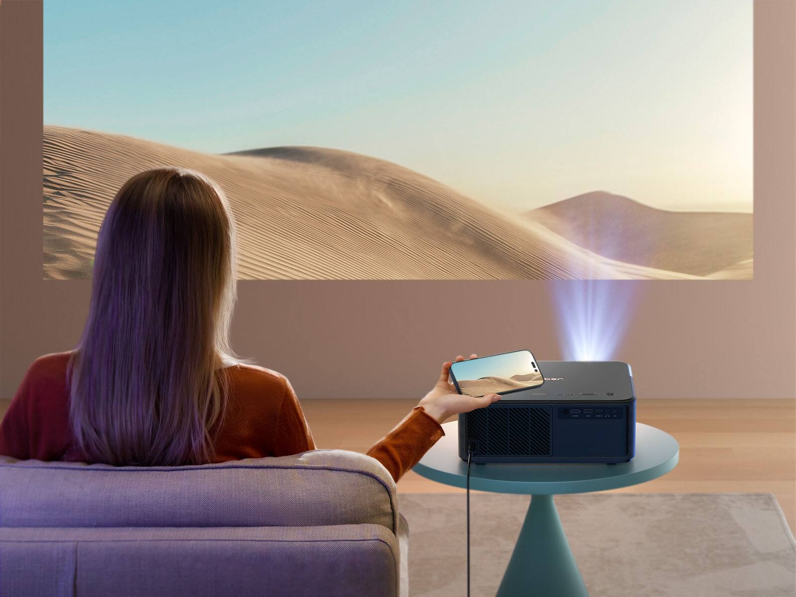 The text on the image reads "a woman sitting in a chair watching a projected image of a desert."