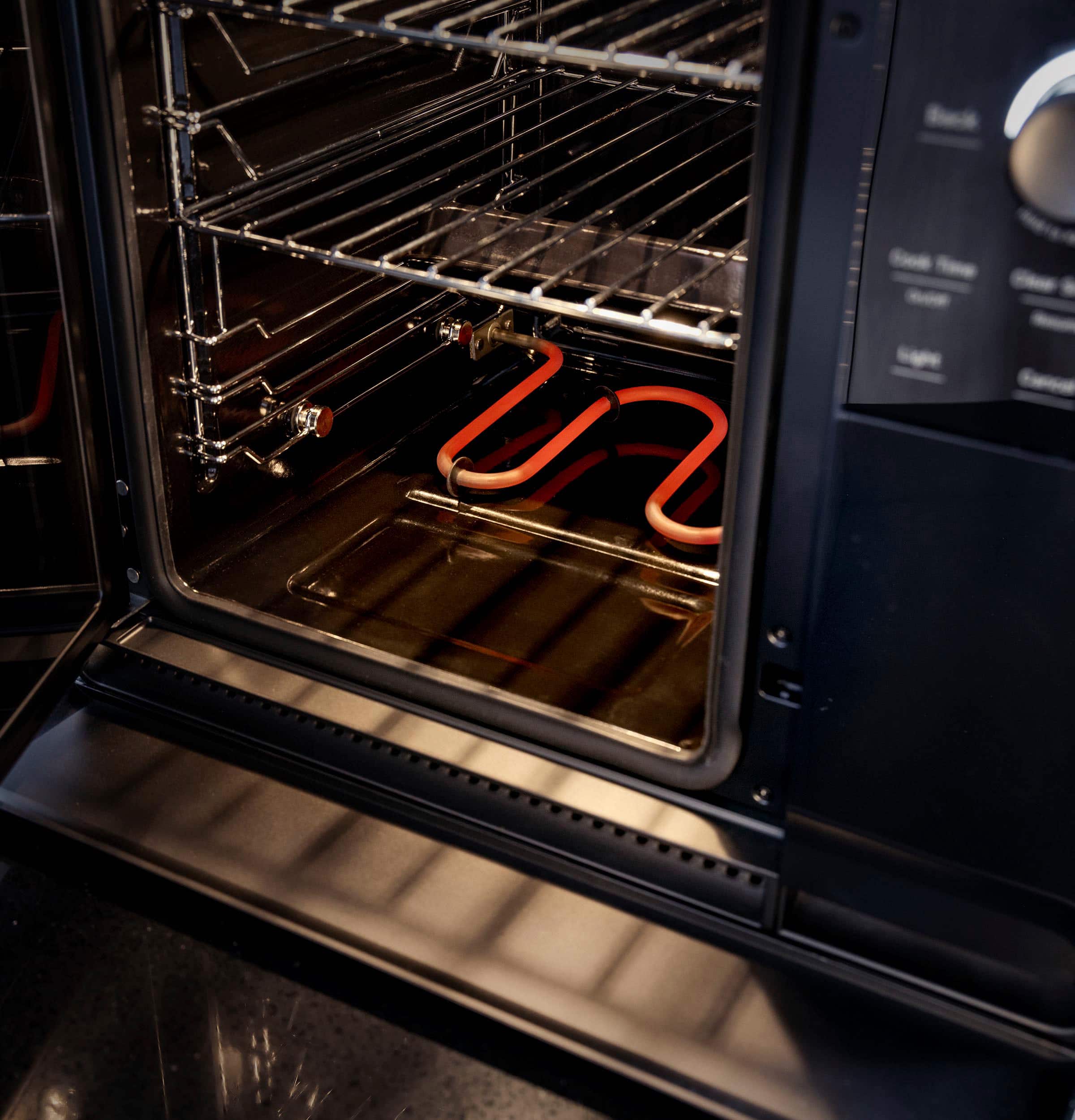 The image features a black oven with two pieces of meat inside, possibly pork ribs. The oven has a digital display and a timer, indicating that it is a modern appliance. The meat is being cooked in the oven, and the oven is likely being used for smoking or roasting the ribs. The oven is also described as a "smoker" and "probe" oven, suggesting that it has advanced features for cooking and monitoring the meat. The oven has been recognized as the "Best in Show" at the CES 2024 event, showcasing its innovative design and functionality.