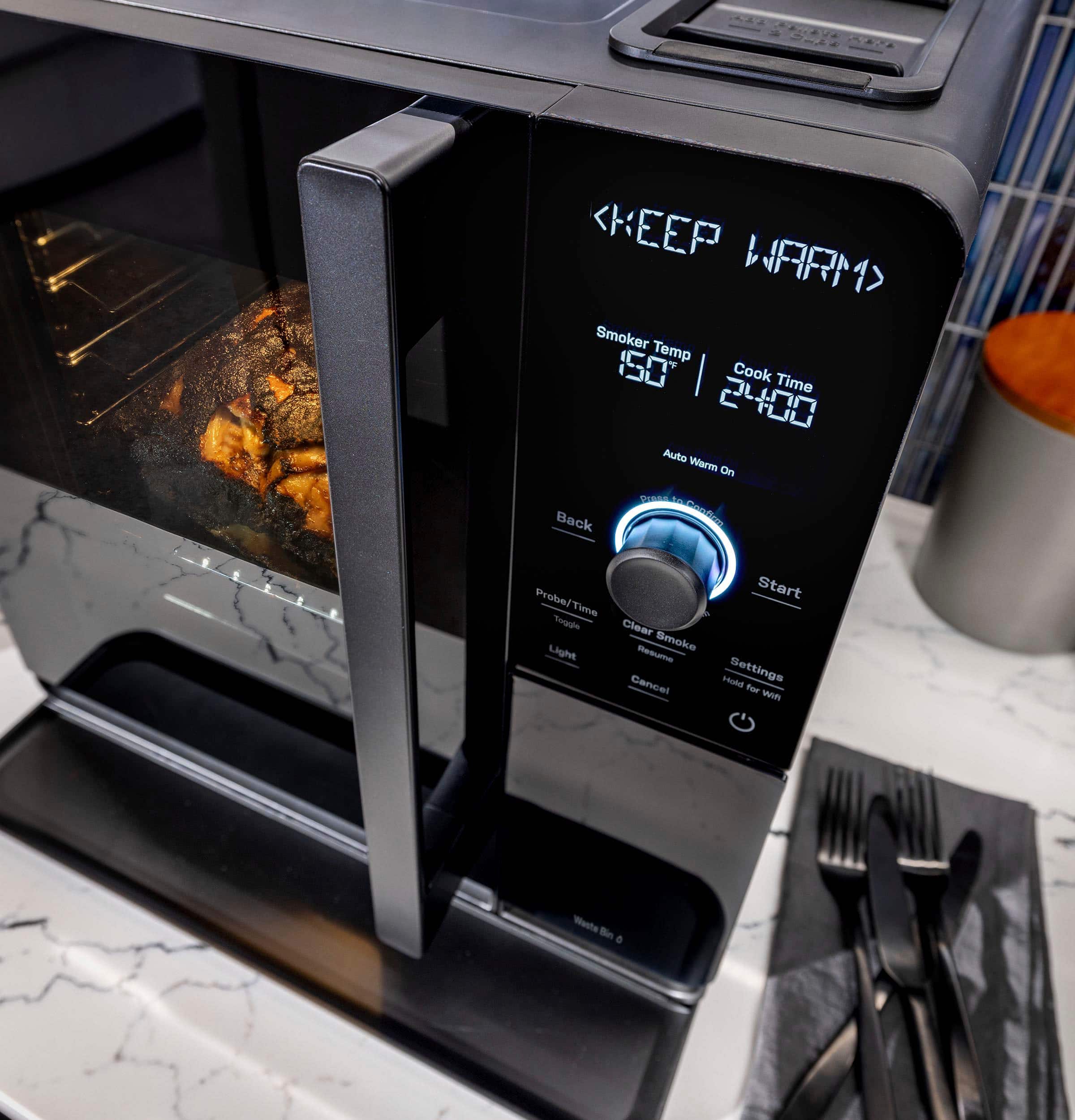The image features a close-up of a black oven with a dishwasher safe racks and drip pan. The oven is equipped with a digital display, which shows the temperature and cooking time. The oven is designed to maintain a consistent temperature of 250 degrees Fahrenheit for smoking brisket, ensuring a delicious and tender result. The oven also has a clear smoke setting, allowing users to adjust the smoke level according to their preference. The oven's back start feature ensures that it can be preheated and ready for use even when the power is turned off and back on.