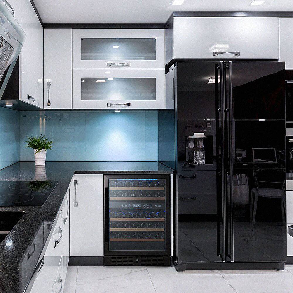 The image shows a kitchen with a wine refrigerator, a refrigerator, and a sink. The wine refrigerator is located in the middle of the kitchen, while the refrigerator is on the right side. The sink is situated on the left side of the kitchen. The kitchen also features a countertop with a potted plant on it.