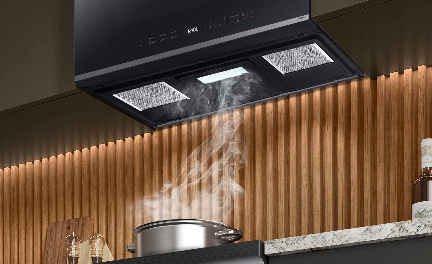 The image shows a kitchen with a stove top and a pot on it. The pot is filled with water and is placed on the stove, which is turned on. The stove has an exhaust fan above it, and steam is rising from the pot, indicating that the water is boiling. The kitchen also features a microwave and a countertop.