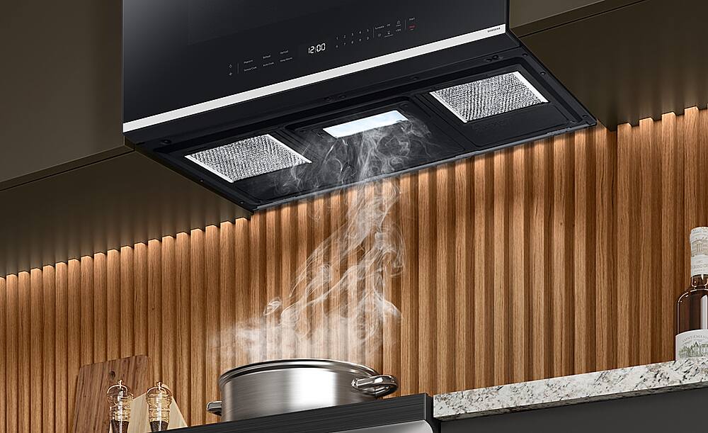 The text on the image reads "12:00 1 I 1 5 . & . - 2 CRAND OR EMILIO." However, this text does not seem to be related to the image of the kitchen. The image shows a stove with steam coming out of it, and the oven is open. The text does not provide any context or information about the scene.