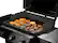 The image shows a grill with a variety of food items on it, including hamburgers, hot dogs, and donuts. The grill is open, revealing the delicious meal being cooked. The grill has a red knob on the front, which is likely used to control the heat or turn the grill on and off. The assortment of food items on the grill indicates that it is being used for a gathering or event where people can enjoy a variety of tasty treats.